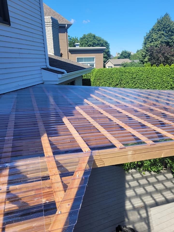 Un toit en plastique transparent est en cours d'installation sur le côté d'une maison.