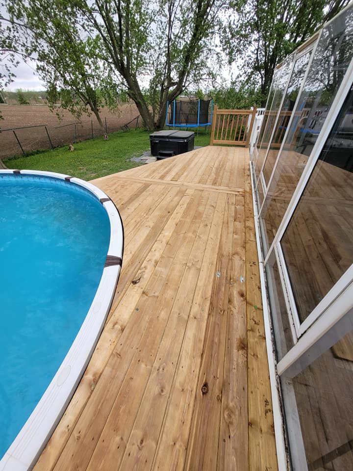 Il y a une terrasse en bois à côté d'une piscine.