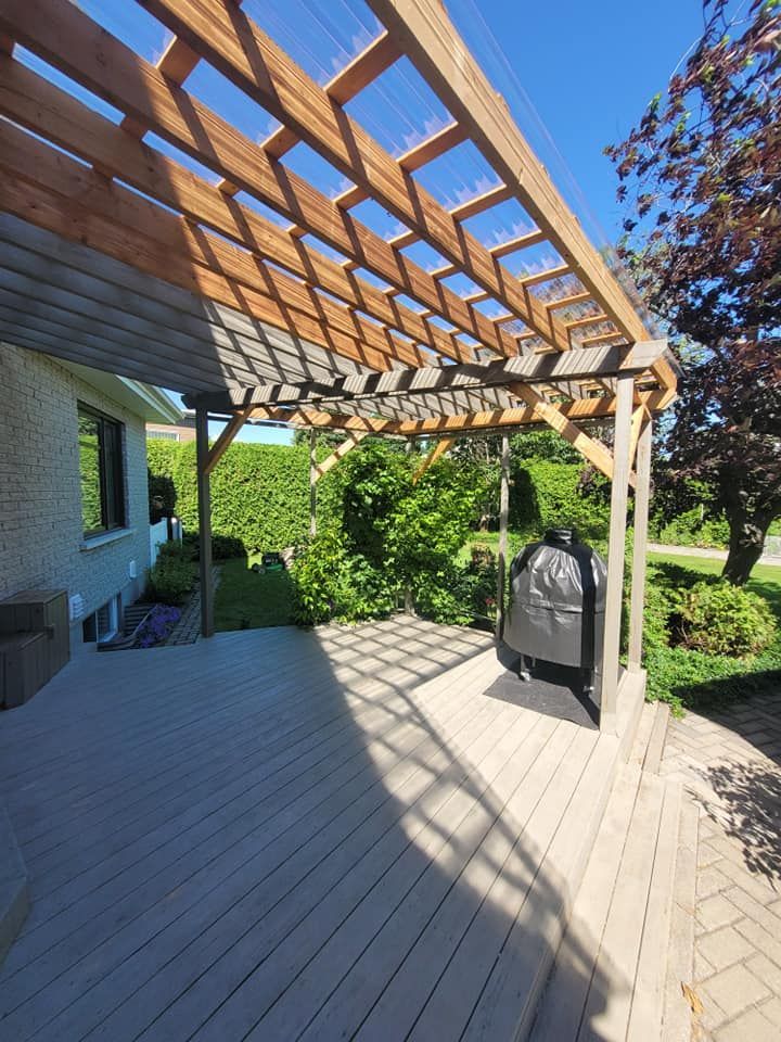 Une terrasse en bois avec une pergola et un barbecue dessus.