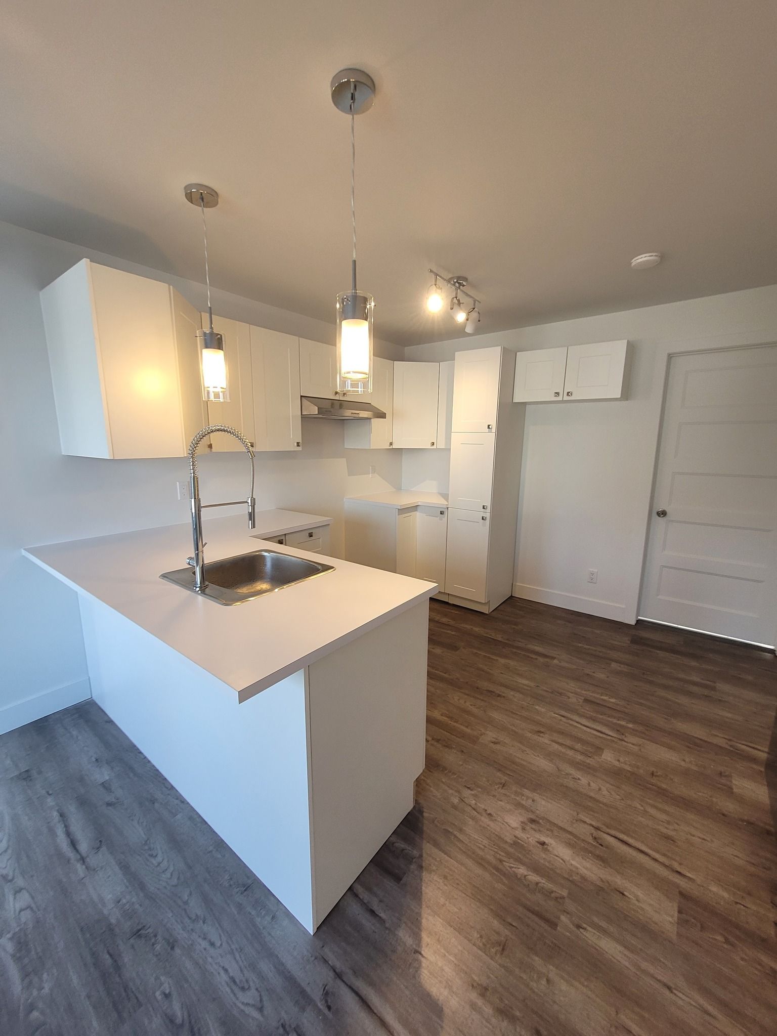 Une cuisine avec des armoires blanches, un évier et un réfrigérateur.