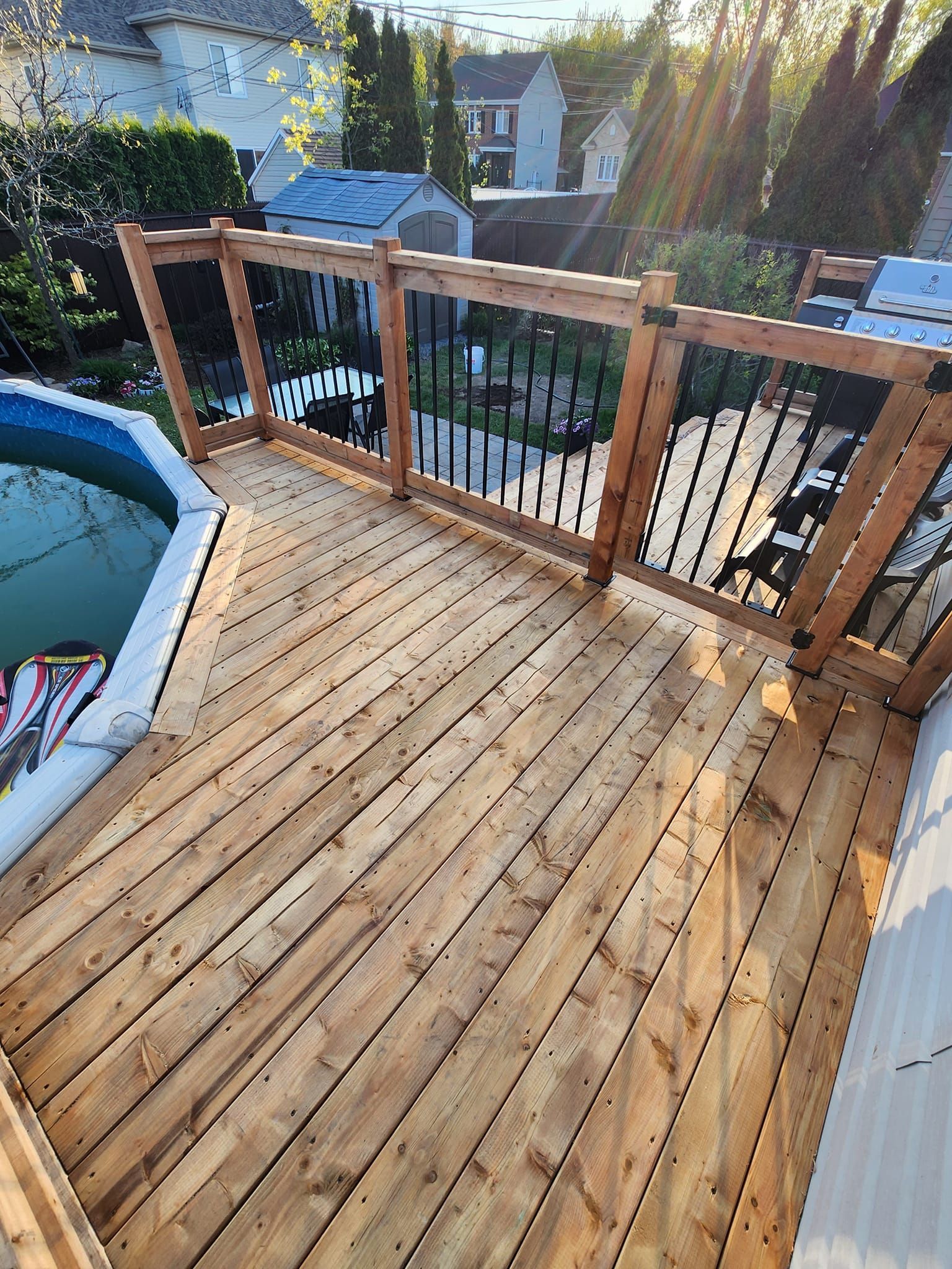 Une terrasse en bois avec une balustrade donnant sur une piscine.
