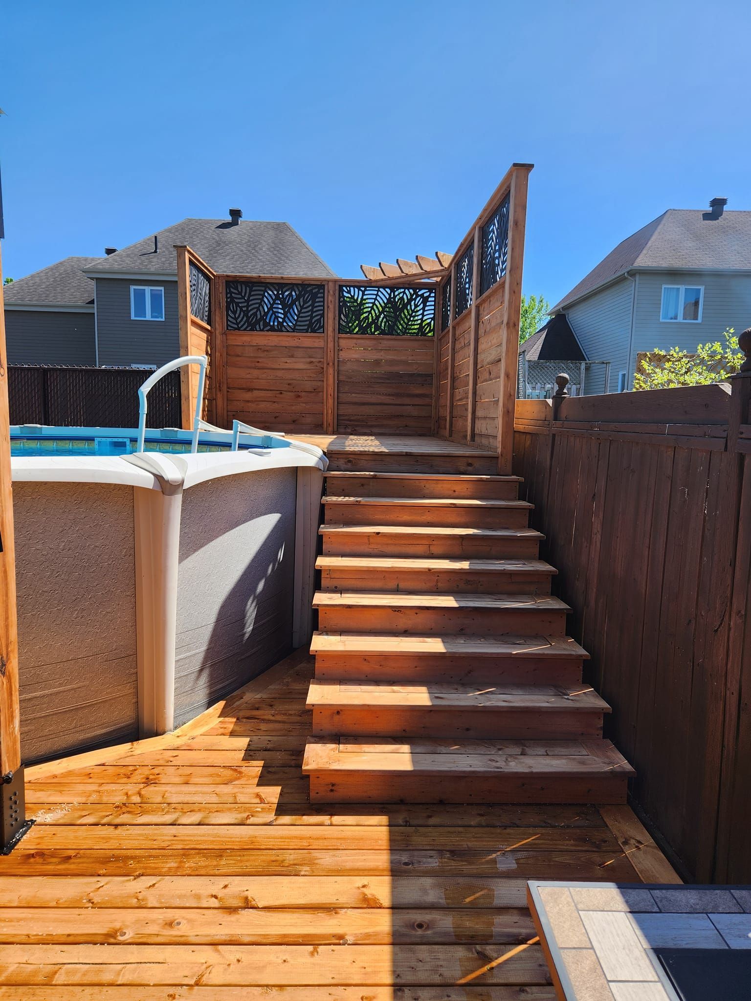 Une terrasse en bois avec des escaliers menant à une piscine.