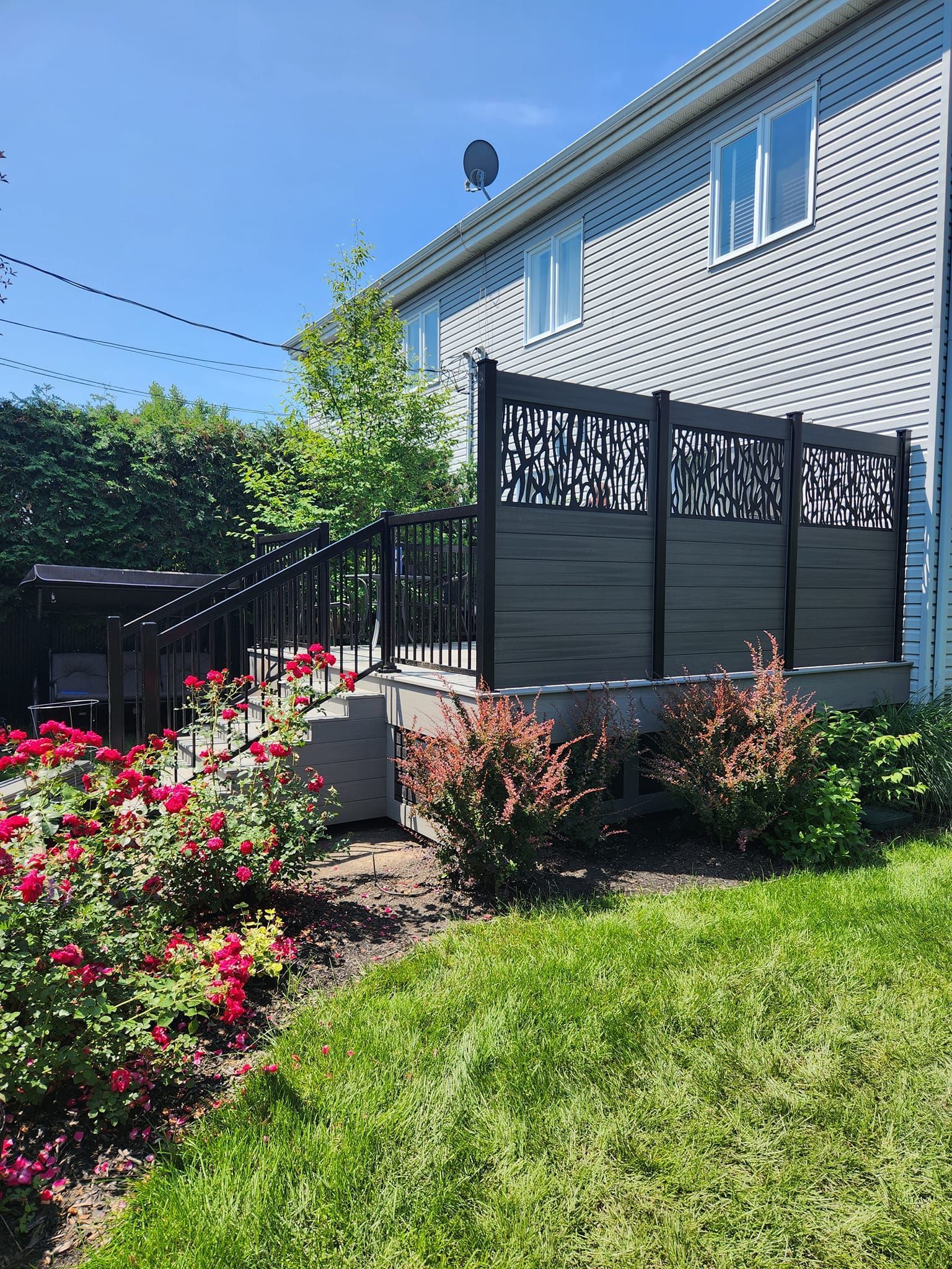 Une maison avec une terrasse et une clôture devant.