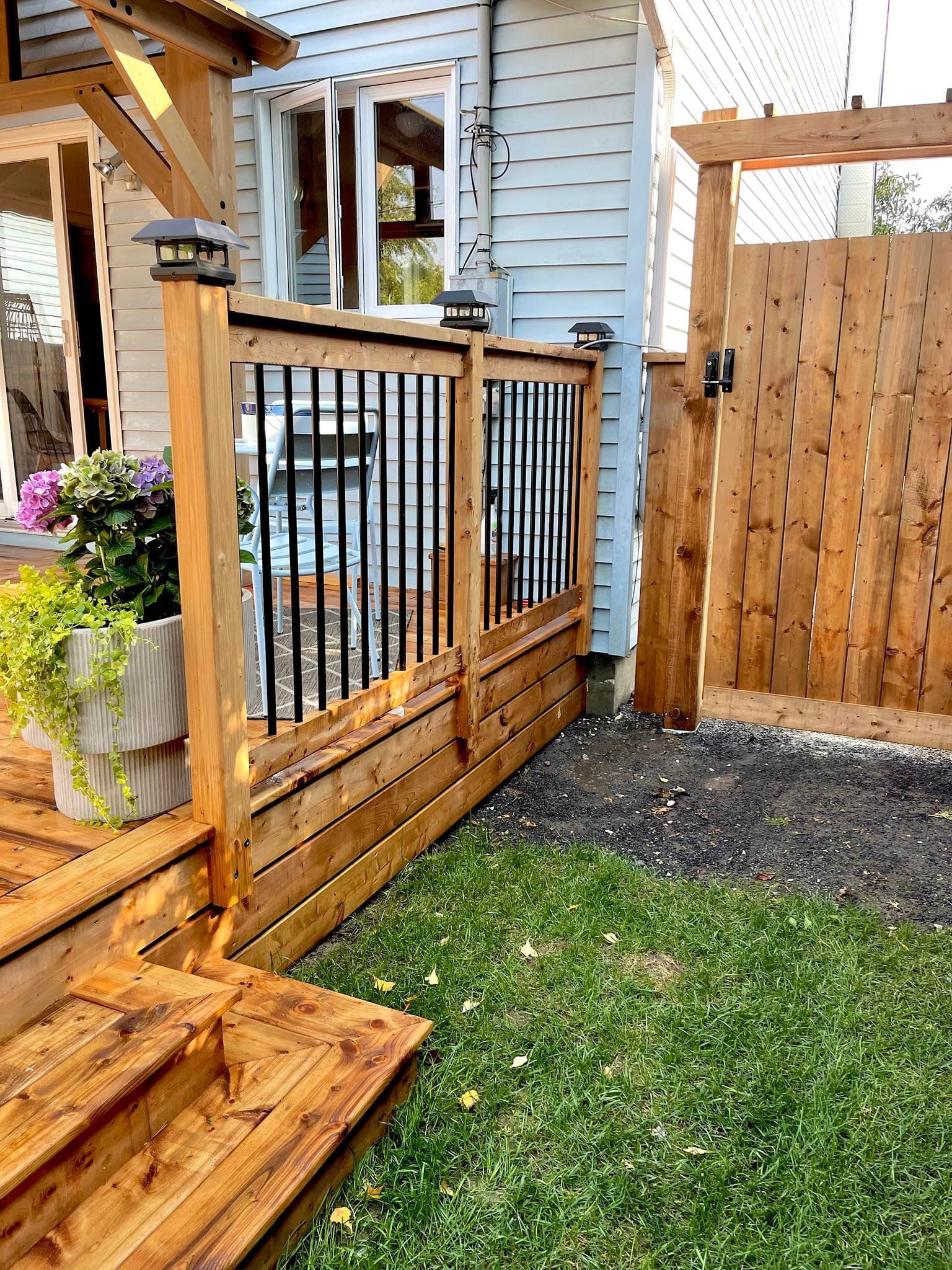 Une terrasse en bois avec des escaliers et une clôture dans l'arrière-cour d'une maison.