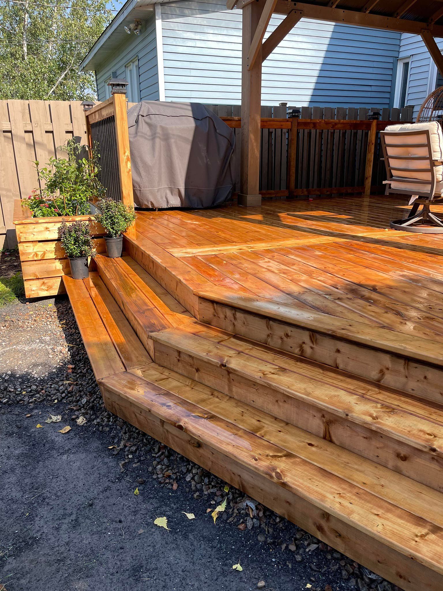 Une terrasse en bois avec des escaliers qui y mènent et une maison en arrière-plan.