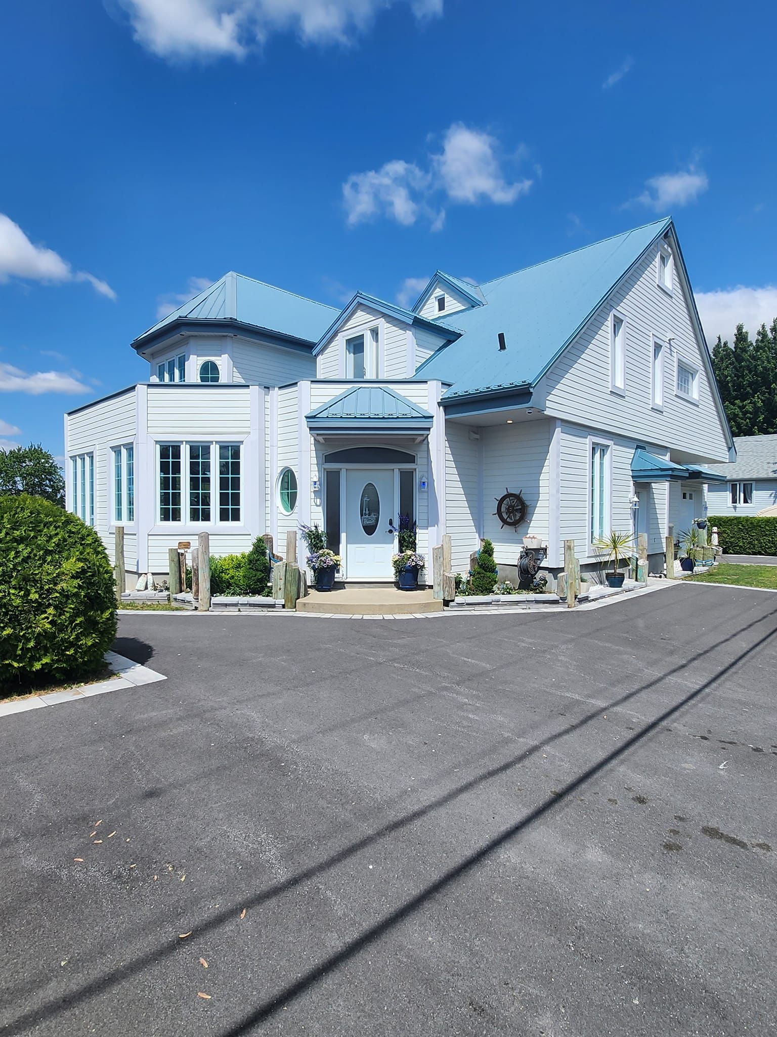 Une grande maison blanche avec un toit bleu et une allée devant.