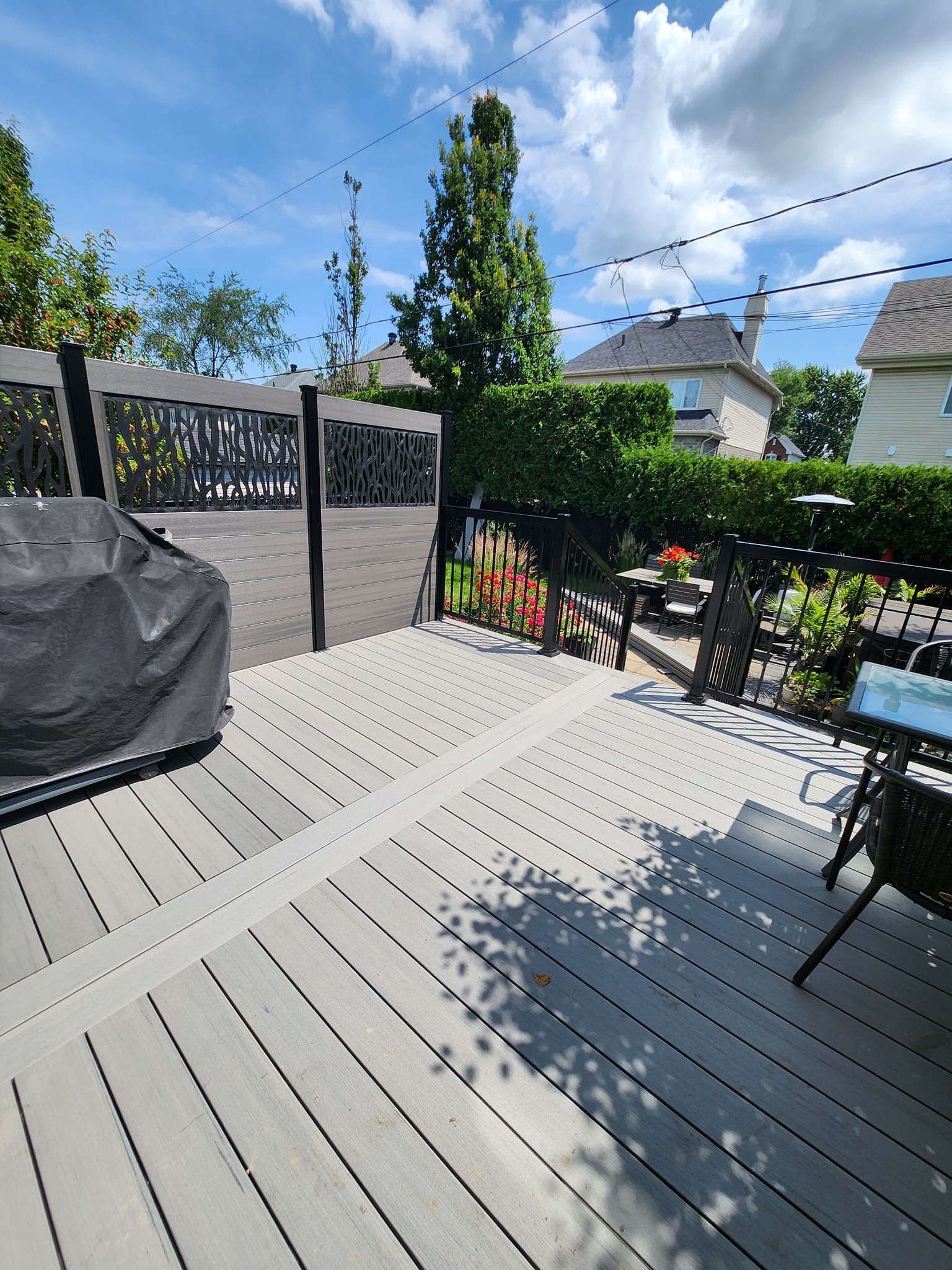 Une terrasse avec une table, des chaises et un barbecue dessus.