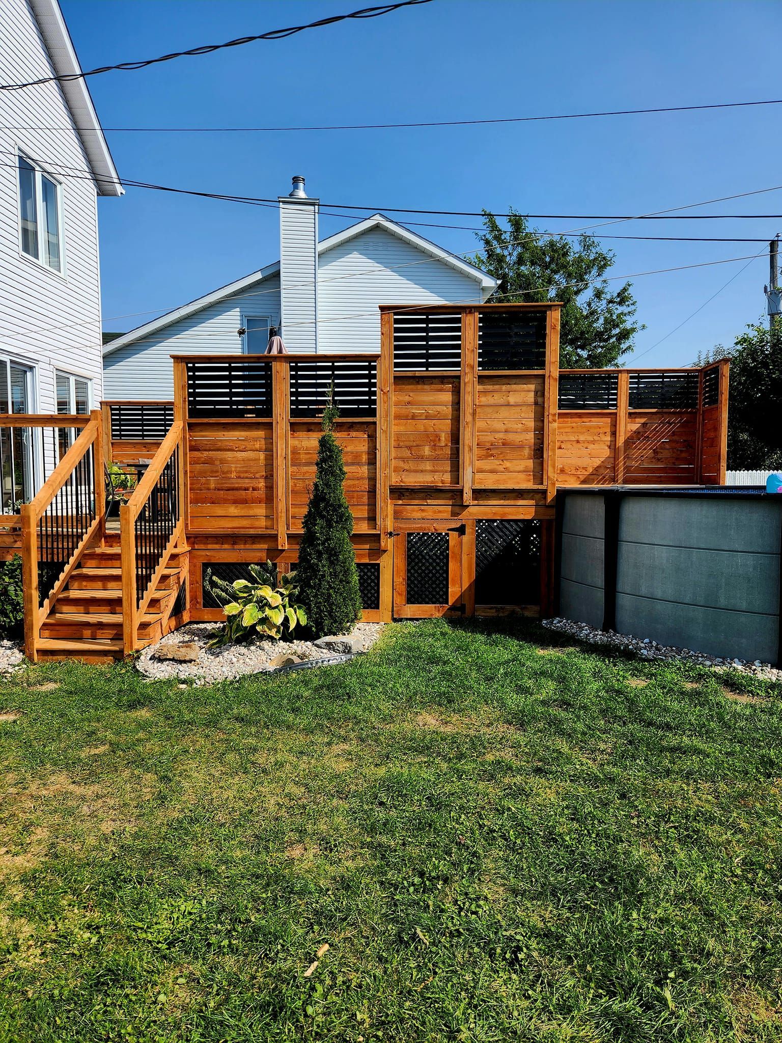 Une terrasse en bois avec des escaliers se trouve dans l'arrière-cour d'une maison.