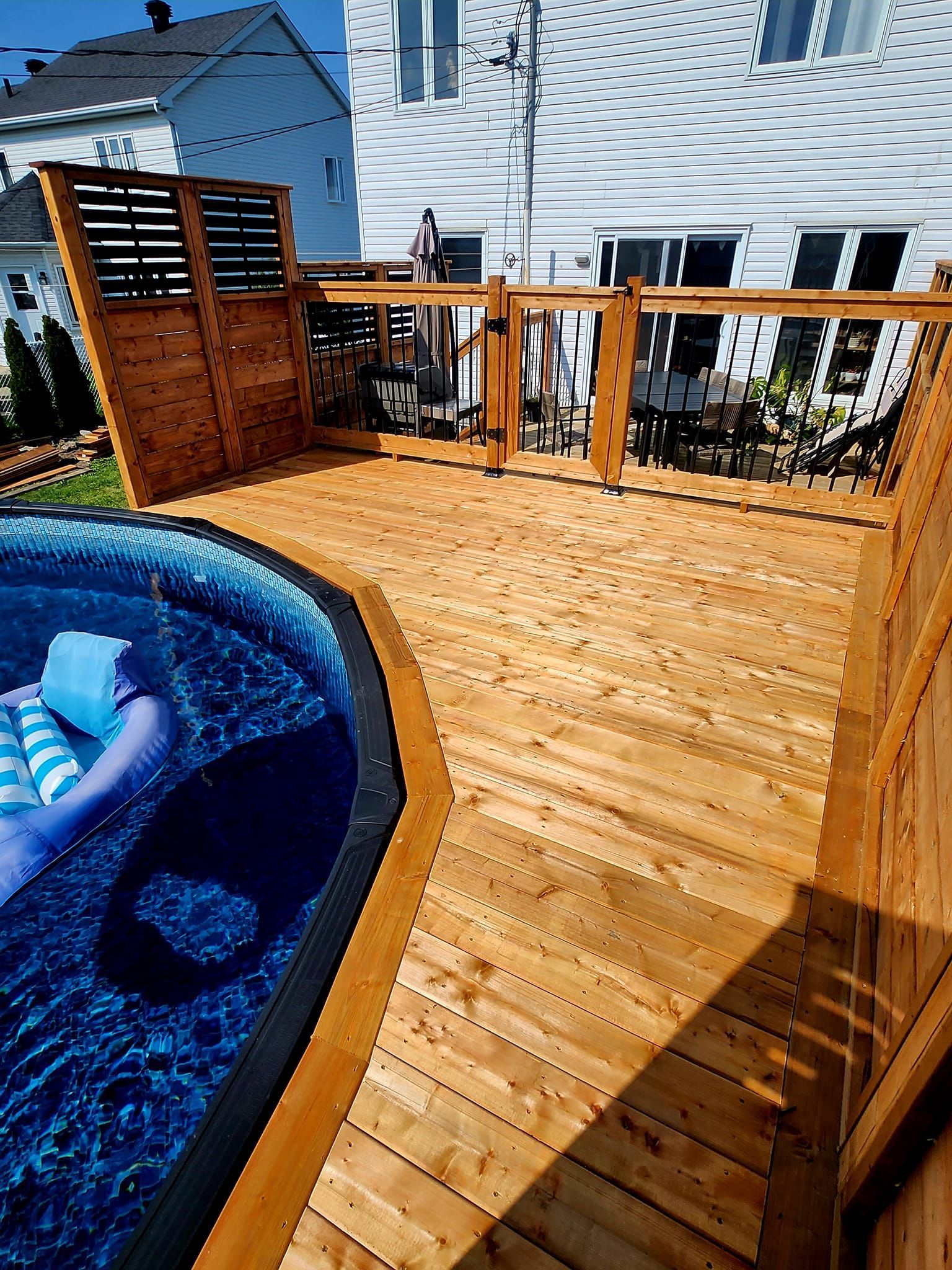 Une terrasse en bois avec un bain à remous en arrière-plan.