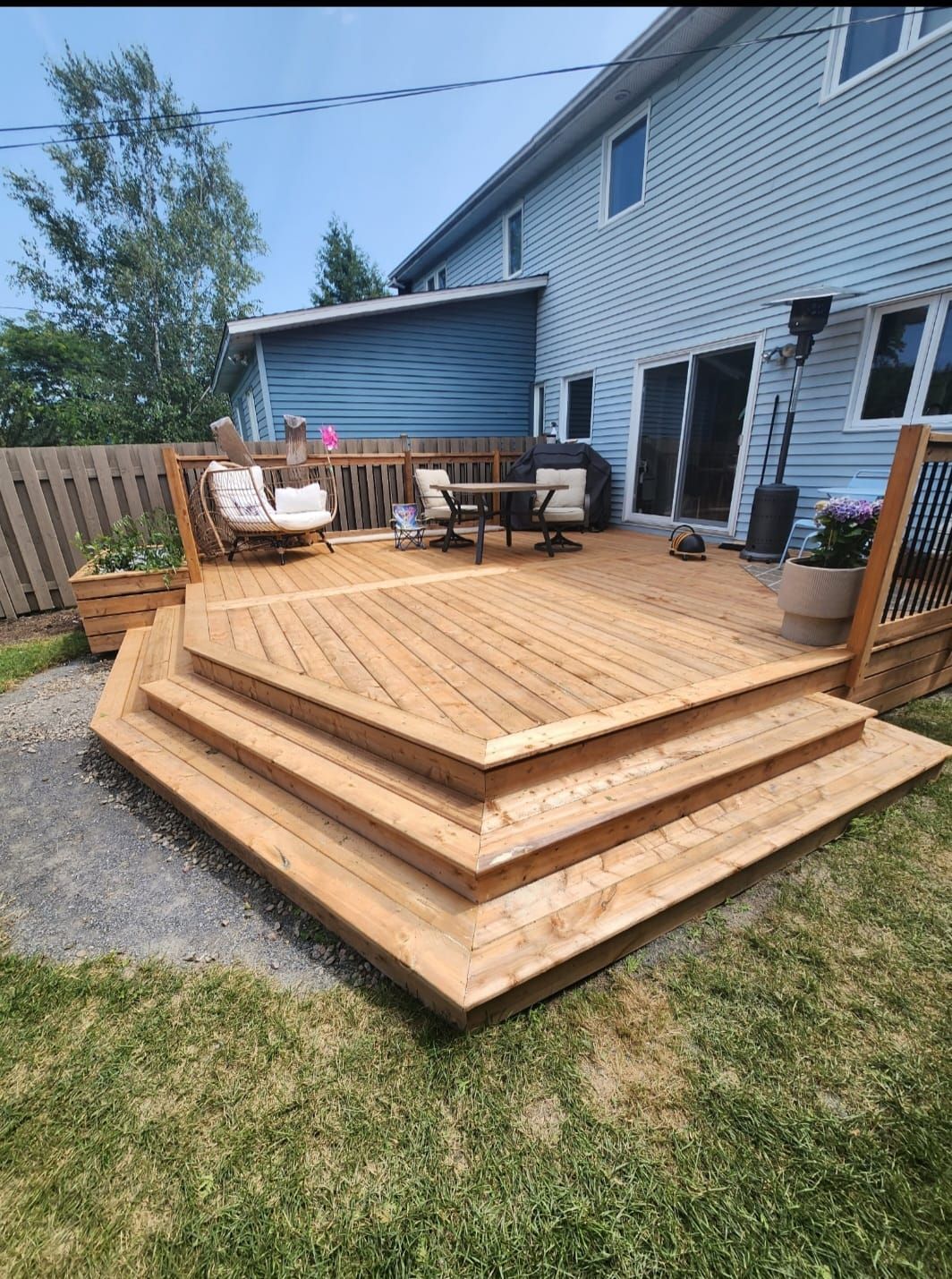 Une terrasse en bois avec des escaliers qui y mènent devant une maison.