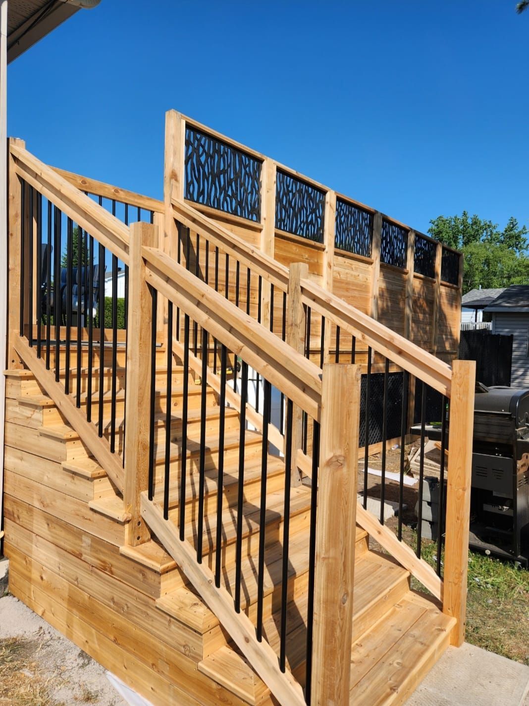 Une terrasse en bois avec des escaliers et une rampe en métal
