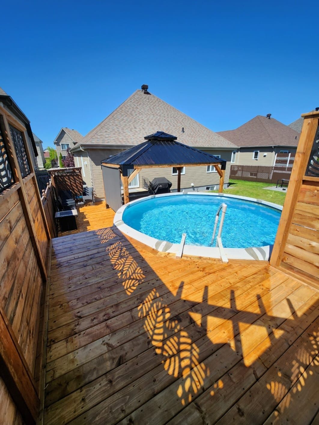 Une grande piscine est entourée d'une terrasse en bois.