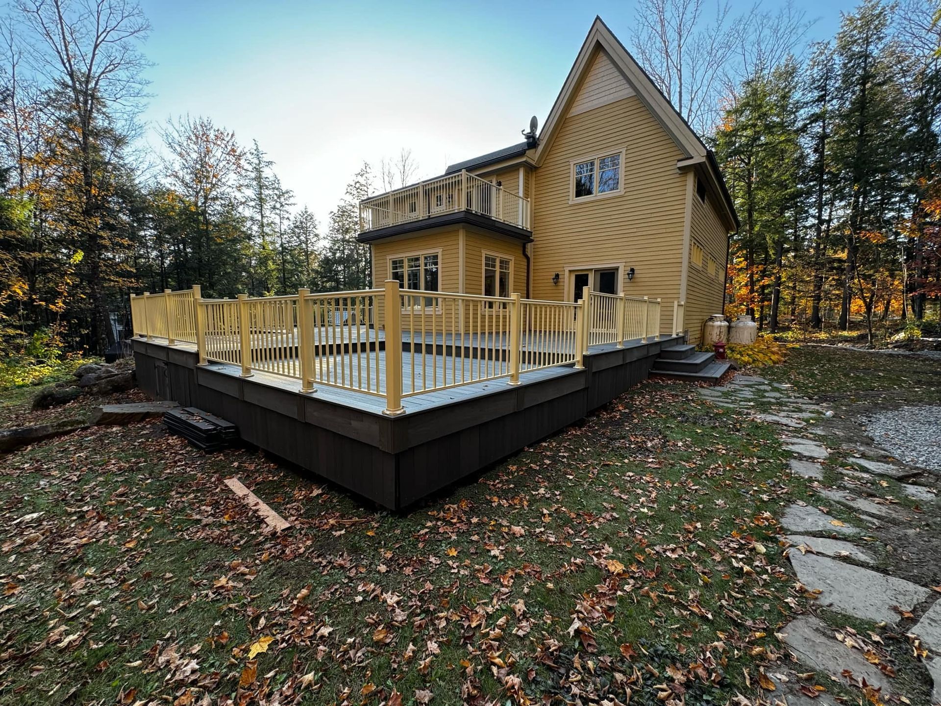 Une maison jaune avec une grande terrasse devant elle