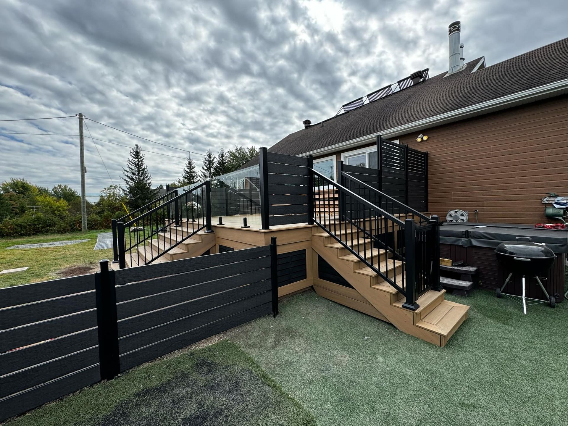 Une terrasse avec des escaliers et une clôture devant une maison.