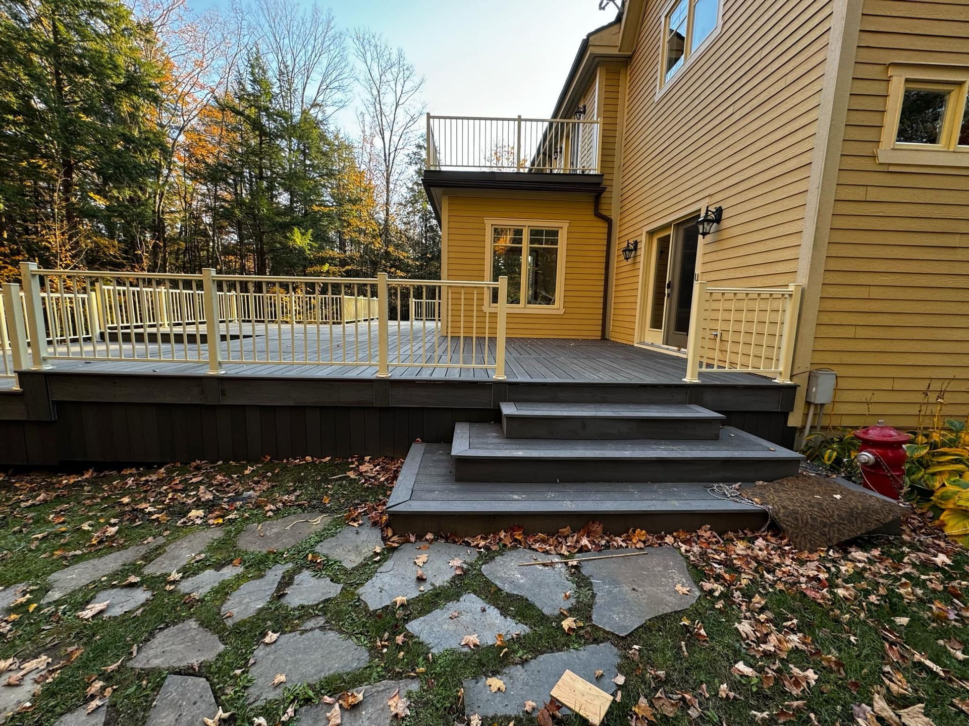 Une grande maison jaune avec une grande terrasse et des escaliers qui y mènent.