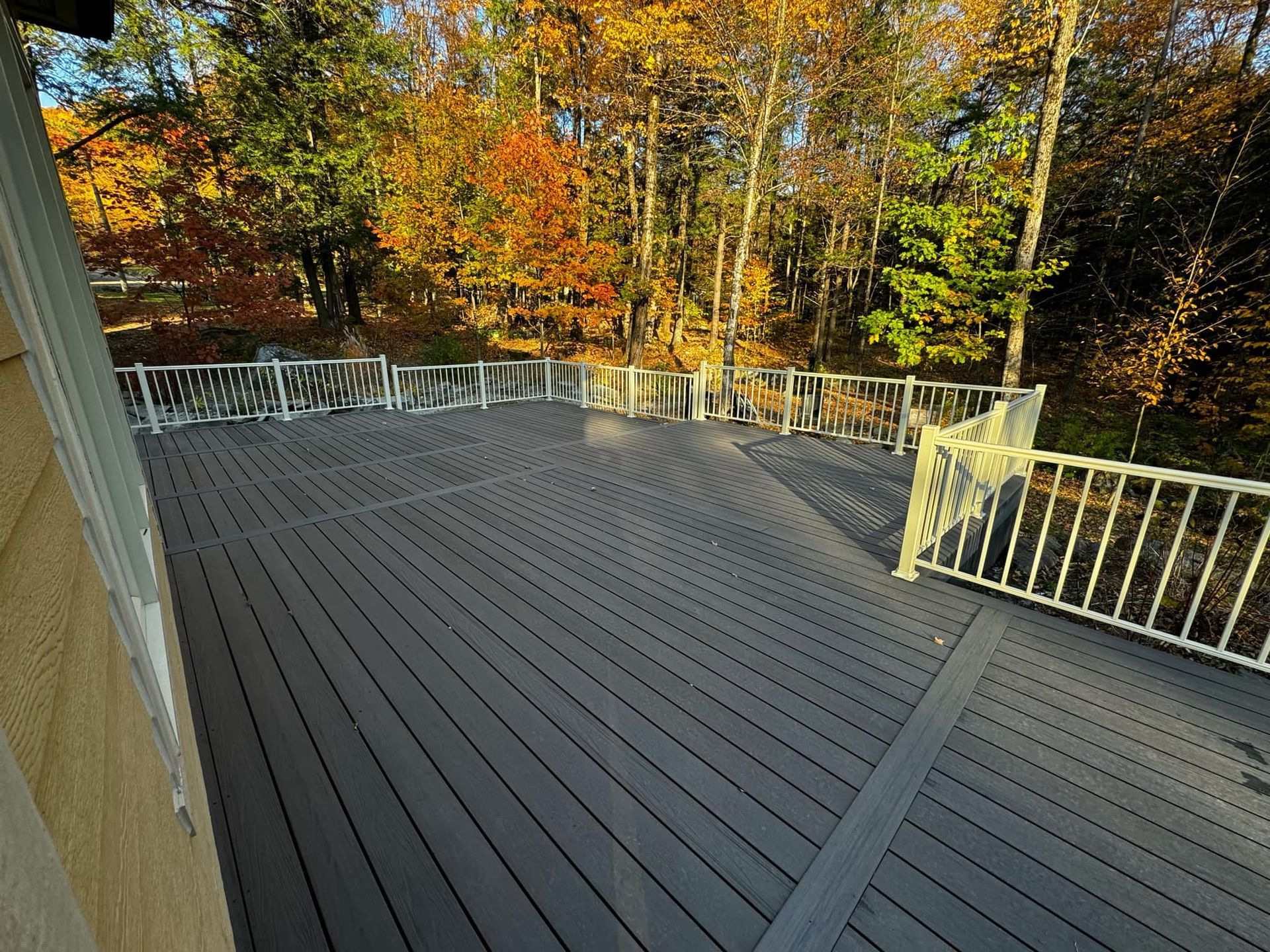 Une grande terrasse grise avec une balustrade blanche et des arbres en arrière-plan.