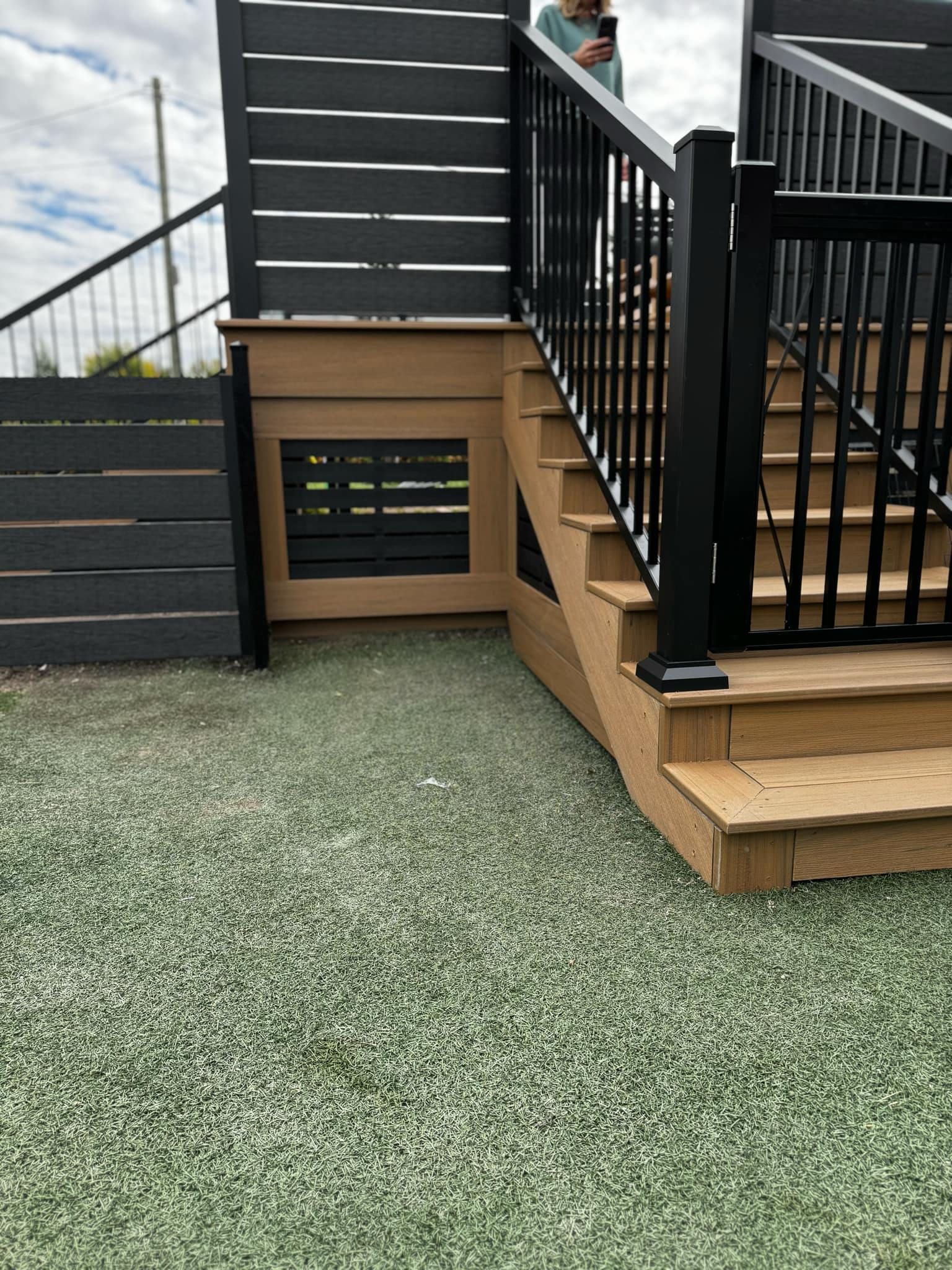 Une personne se tient sur une terrasse avec des escaliers et une clôture.