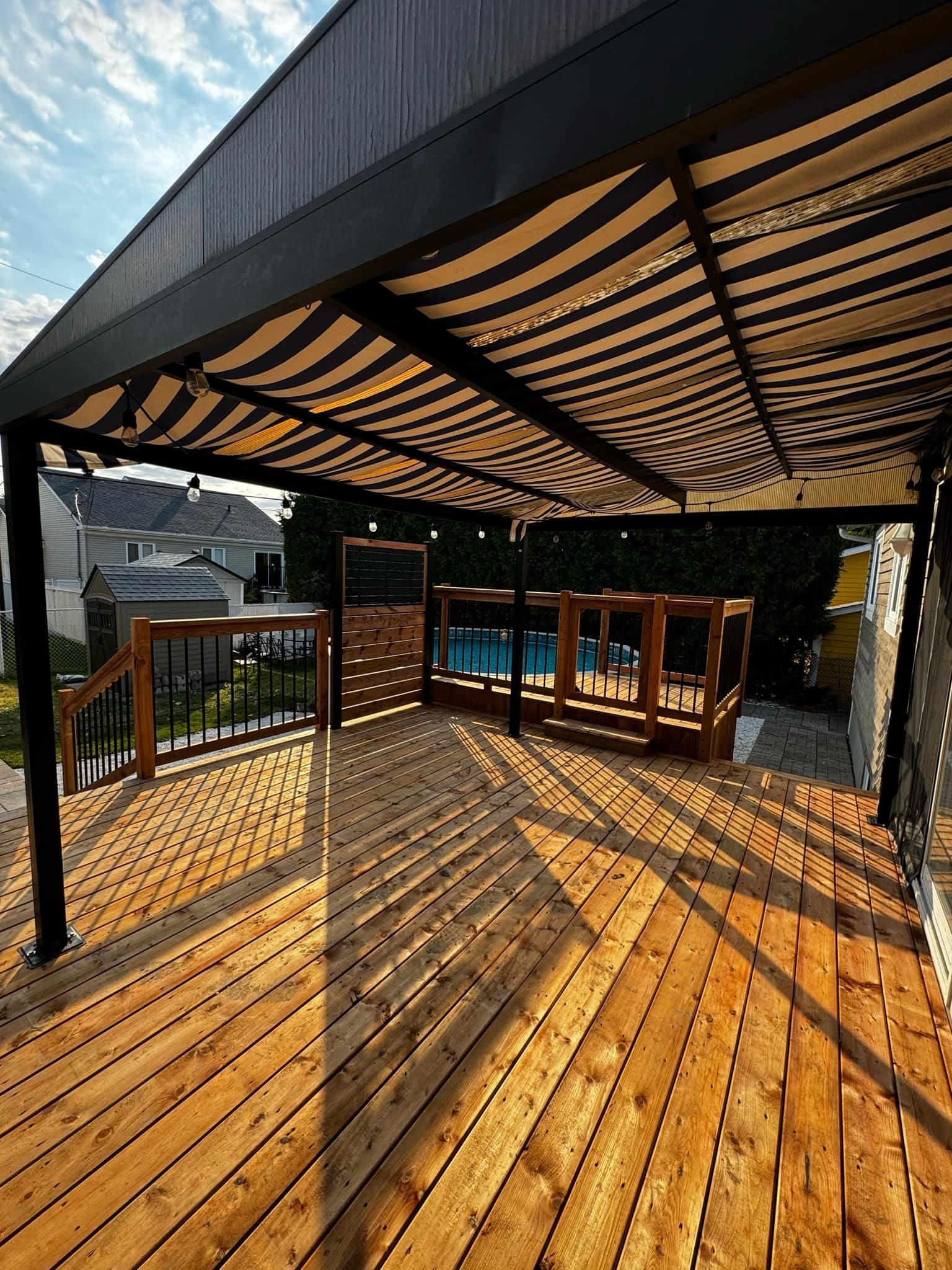Une terrasse en bois avec un auvent au-dessus et une piscine en arrière-plan.