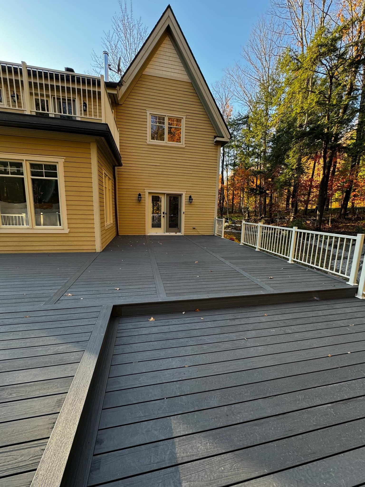 Une grande maison jaune avec une grande terrasse devant elle.