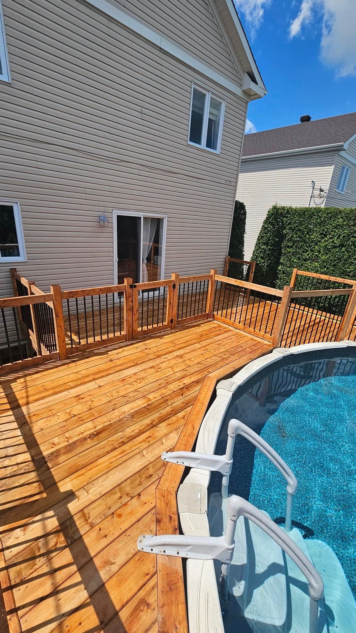 Une terrasse en bois à côté d'une piscine devant une maison.