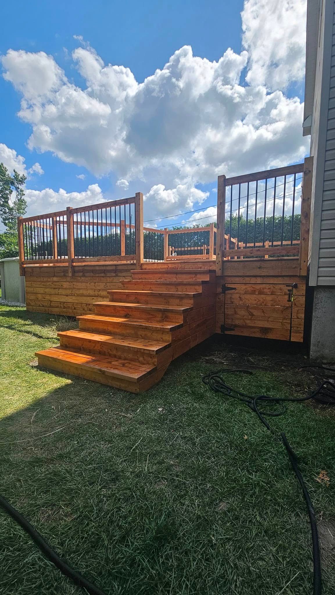 Une terrasse en bois avec des escaliers qui y mènent se trouve dans l'arrière-cour d'une maison.