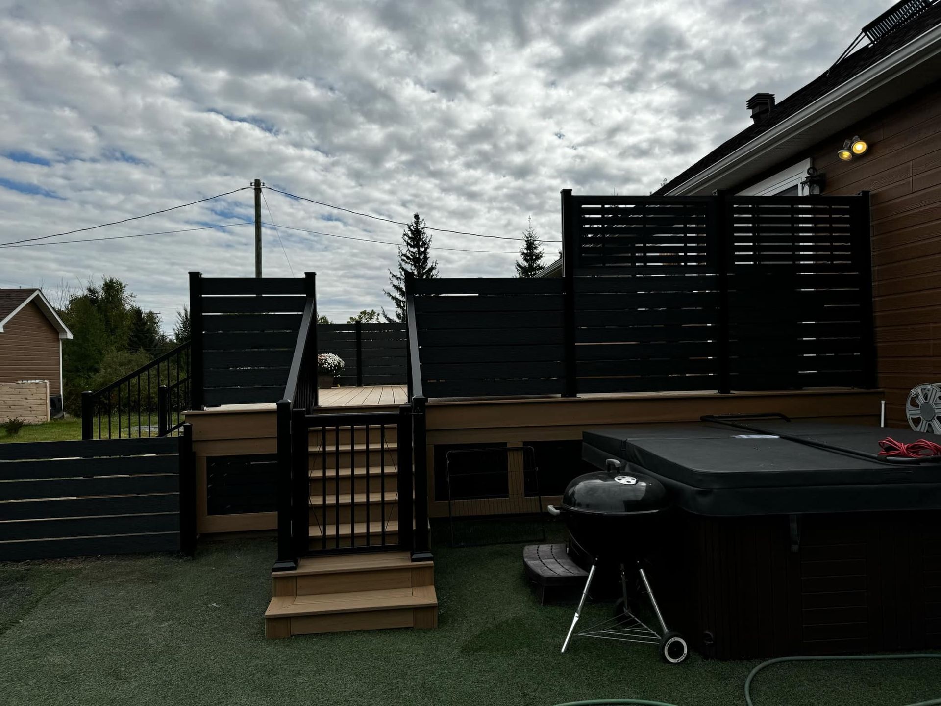Une cour arrière avec un bain à remous, des escaliers et un barbecue.