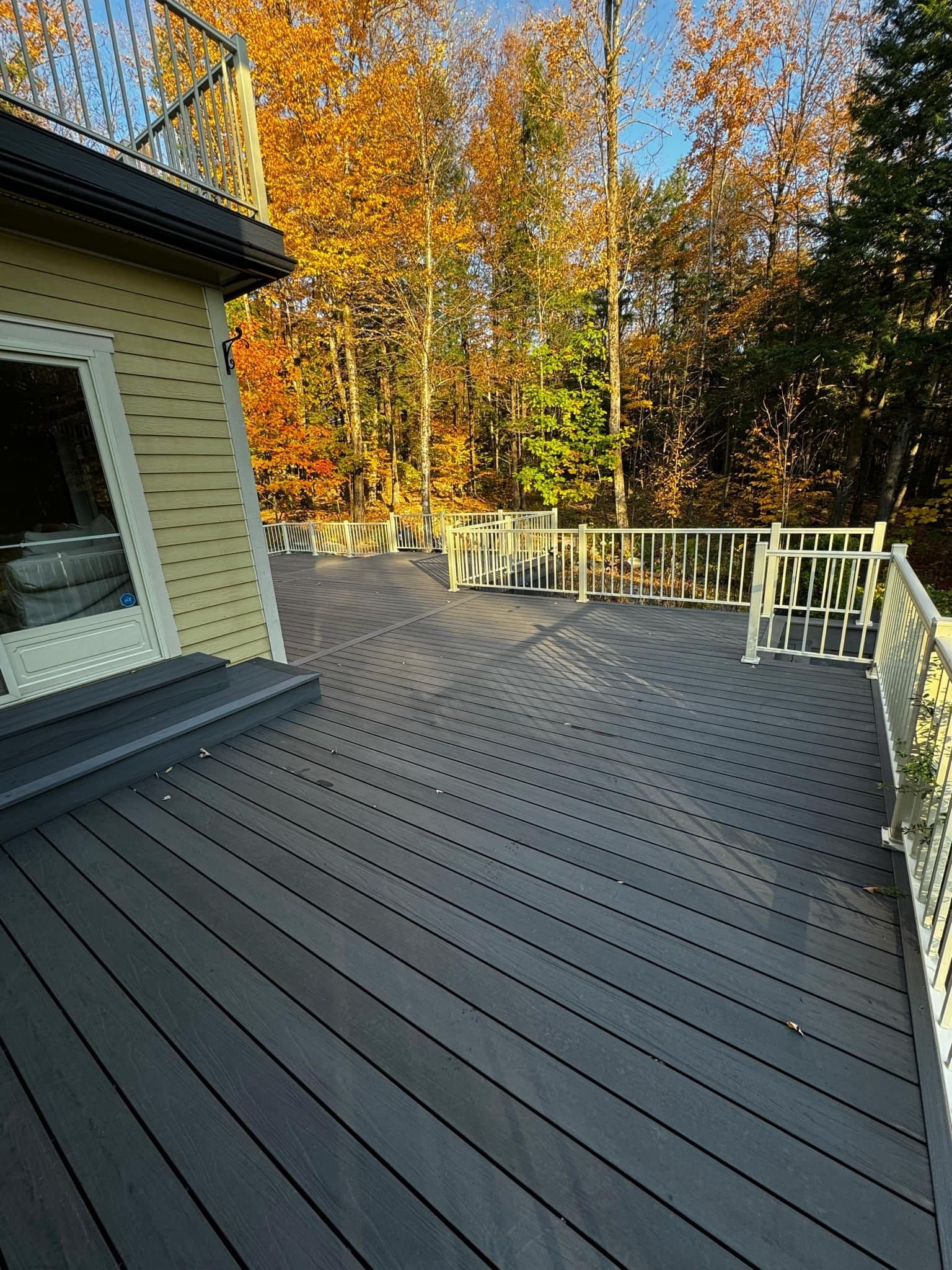 Une grande terrasse avec une balustrade blanche et des arbres en arrière-plan.
