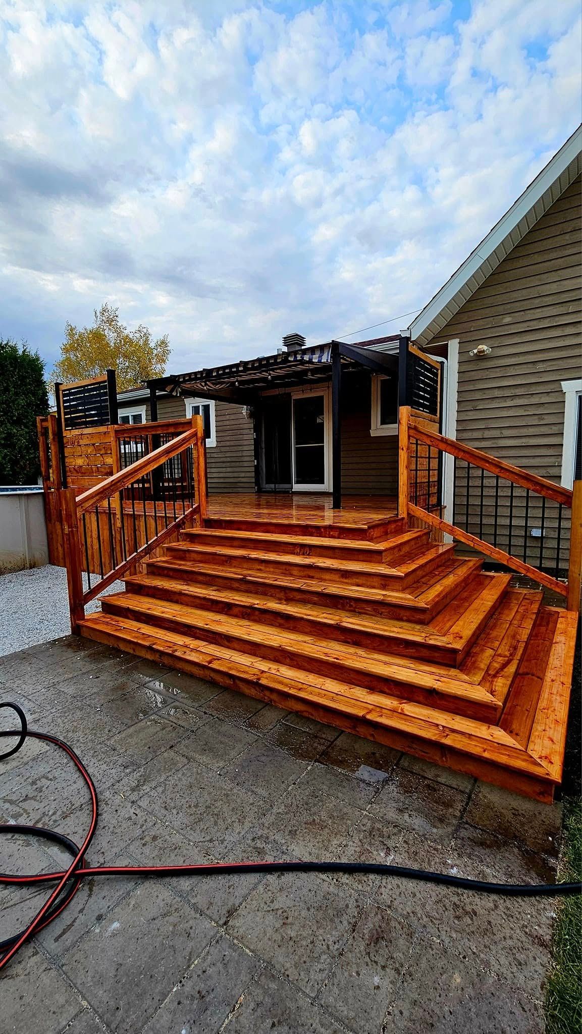 Une terrasse en bois avec des escaliers menant à une maison.