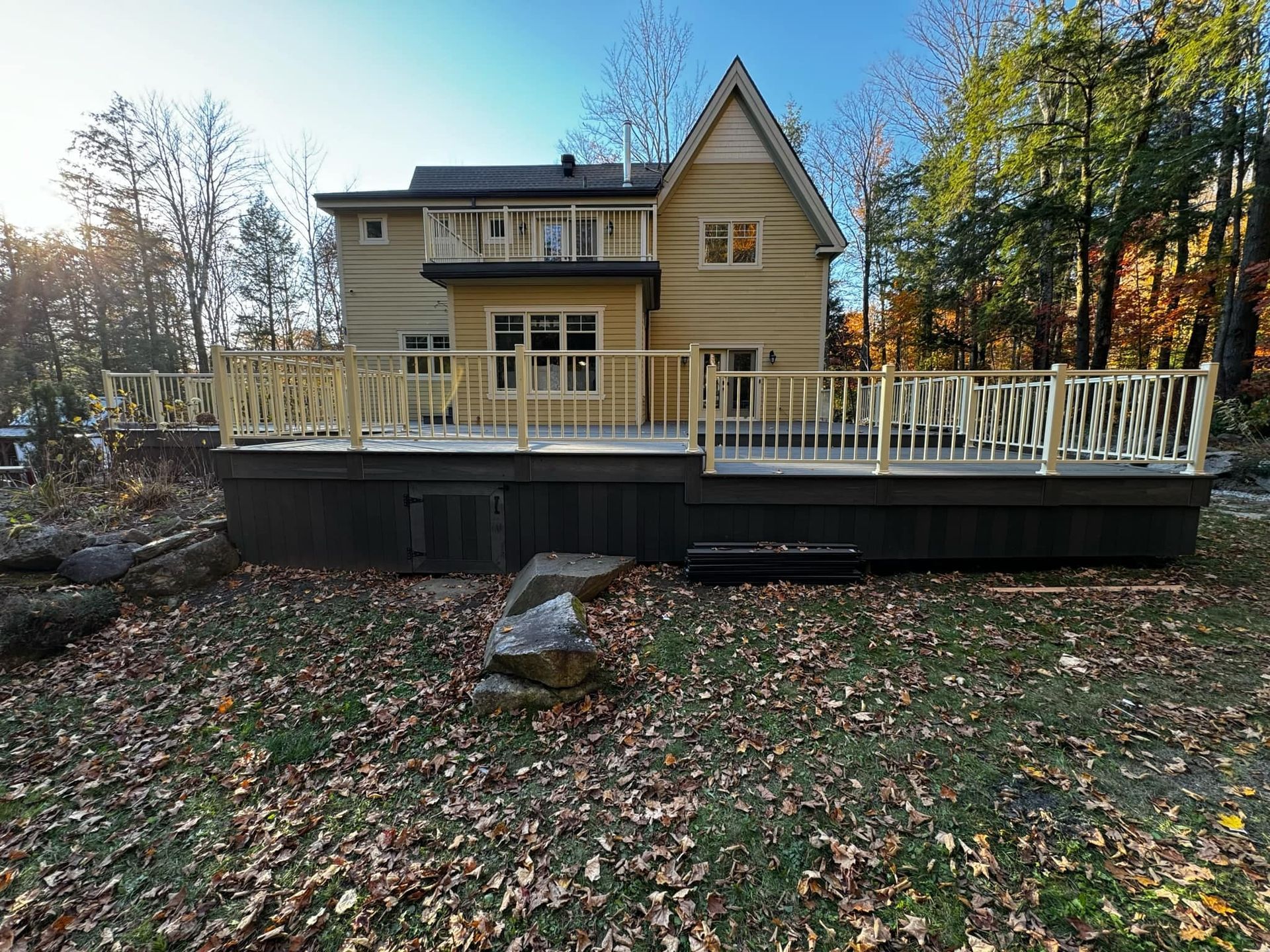 Une grande maison avec une grande terrasse dans l'arrière-cour entourée d'arbres.