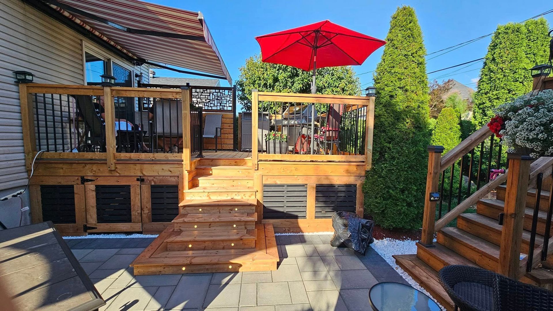 Une terrasse en bois avec un parasol rouge dans l'arrière-cour d'une maison.