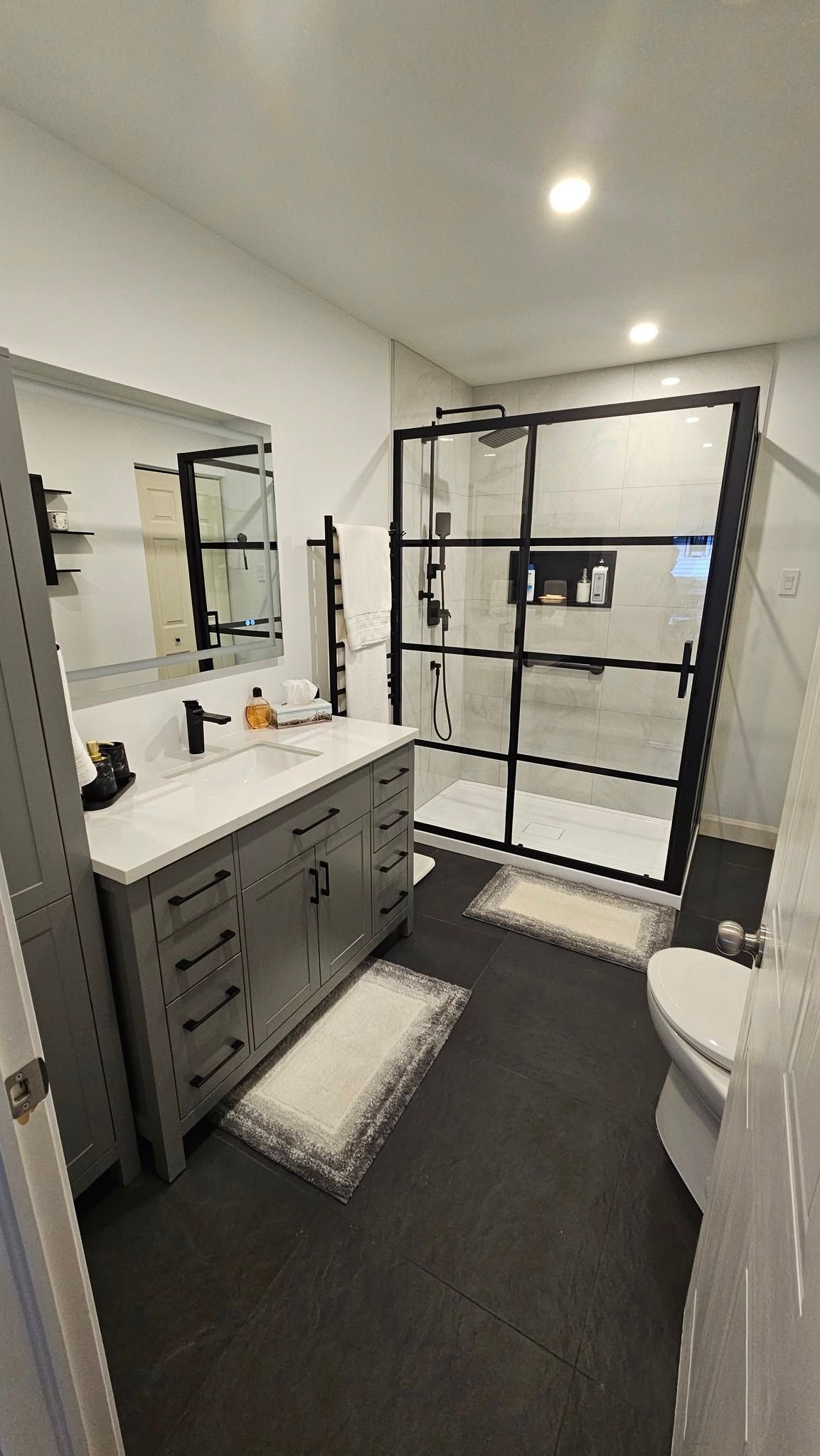 Une salle de bain avec lavabo, WC, douche et miroir.