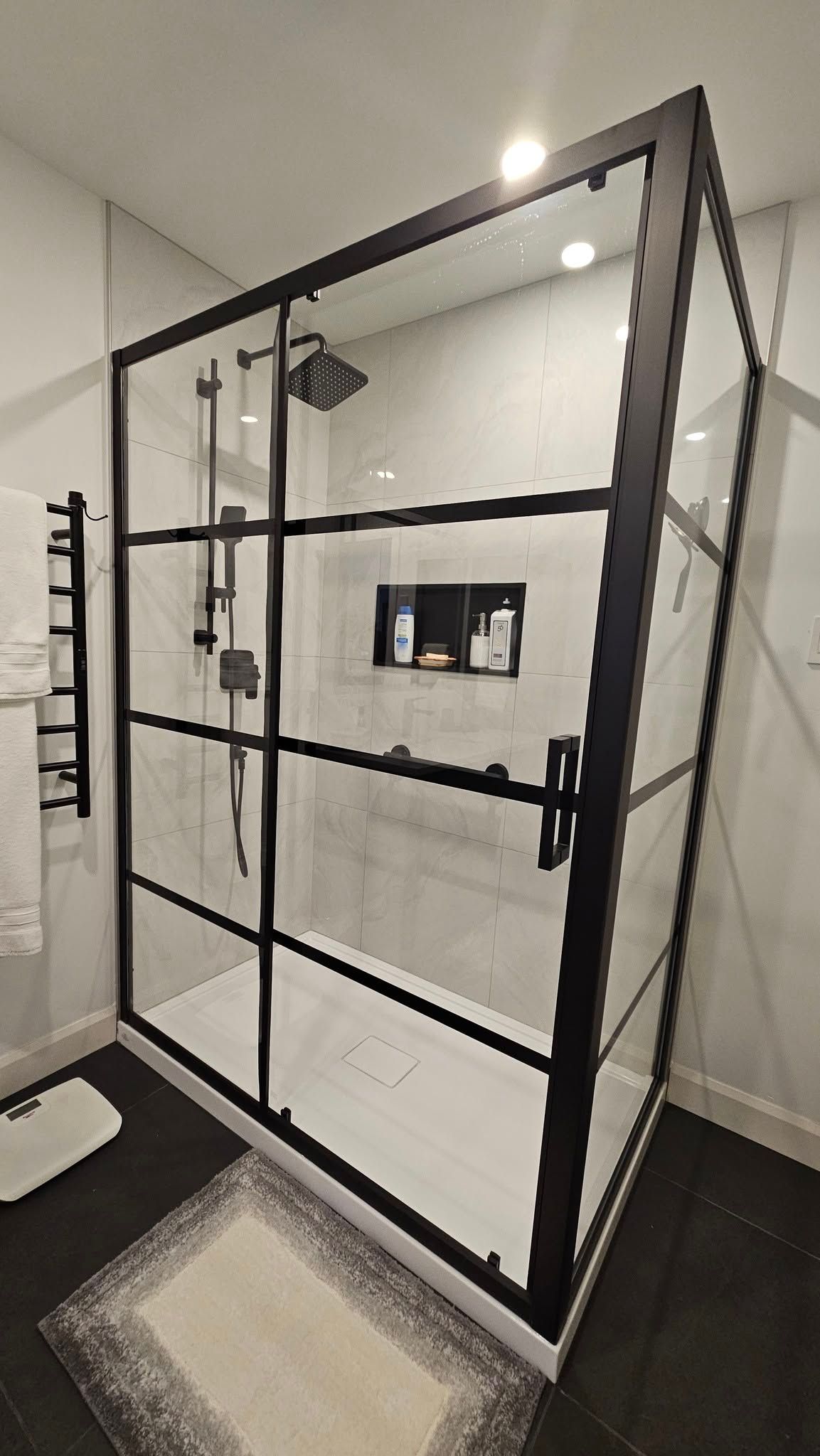 Une salle de bain avec une douche à l'italienne avec un cadre noir.