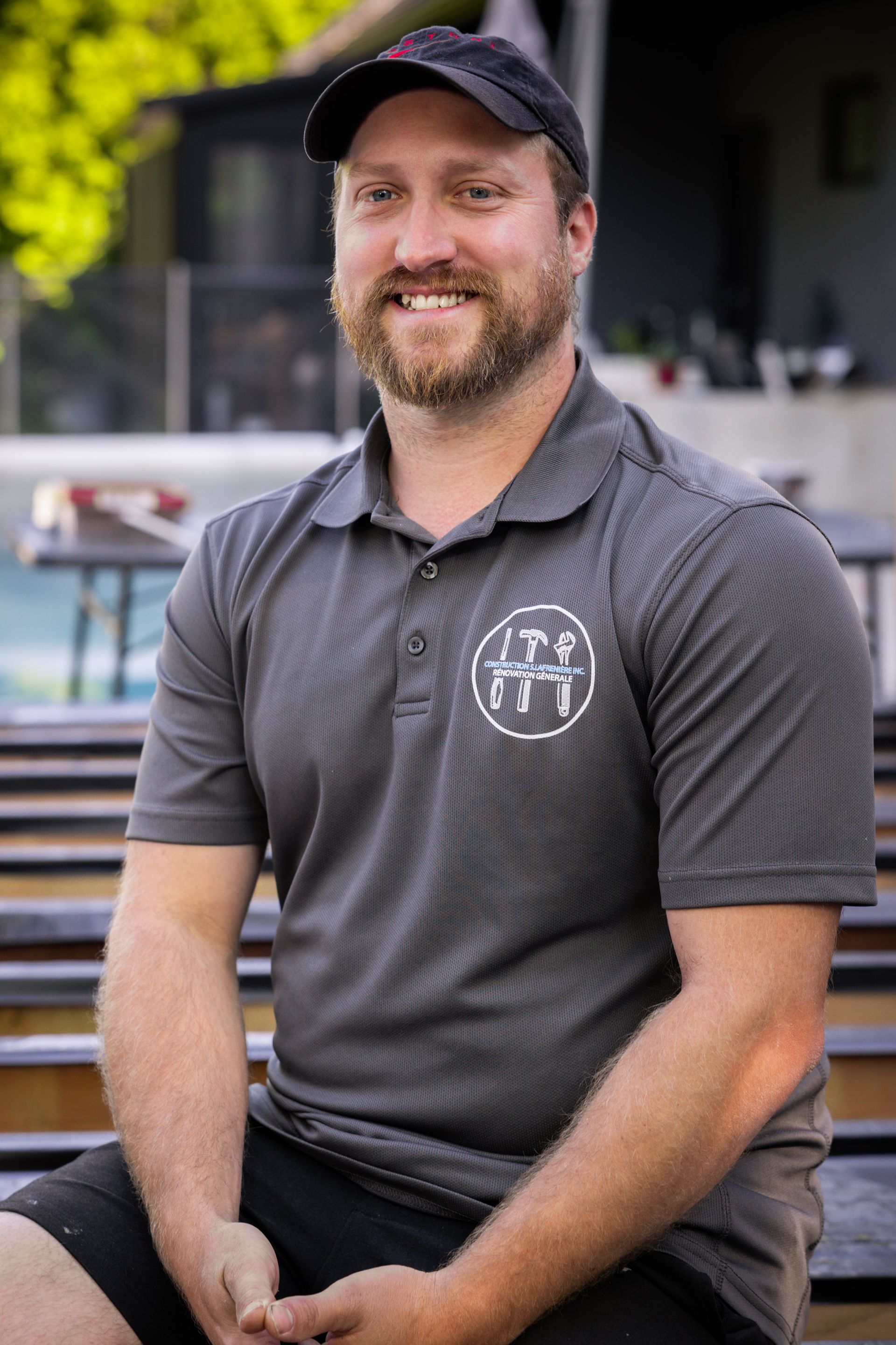 Une femme aux cheveux blonds sourit et porte une chemise noire.