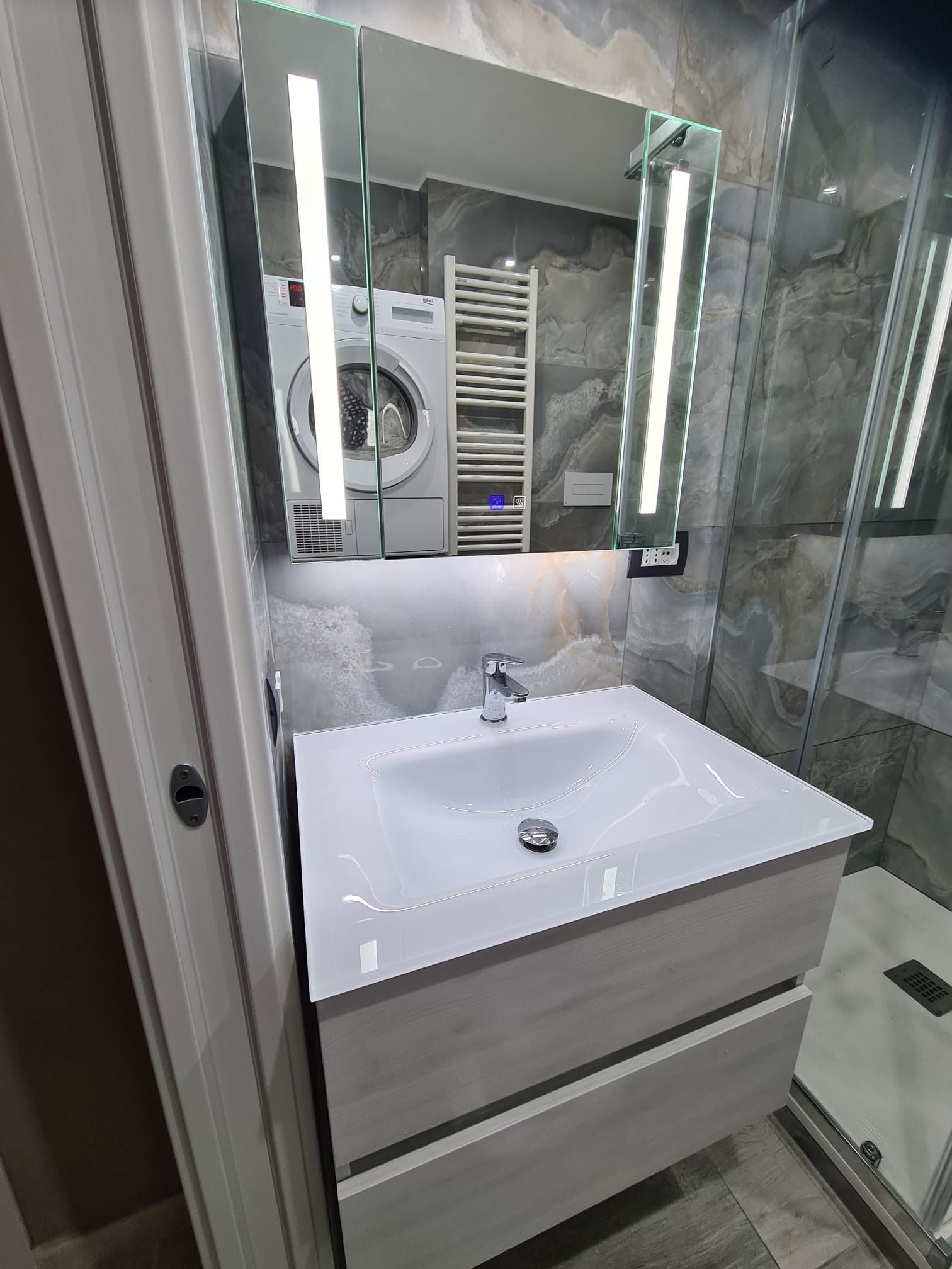 Un bagno con lavandino, specchio e lavatrice.