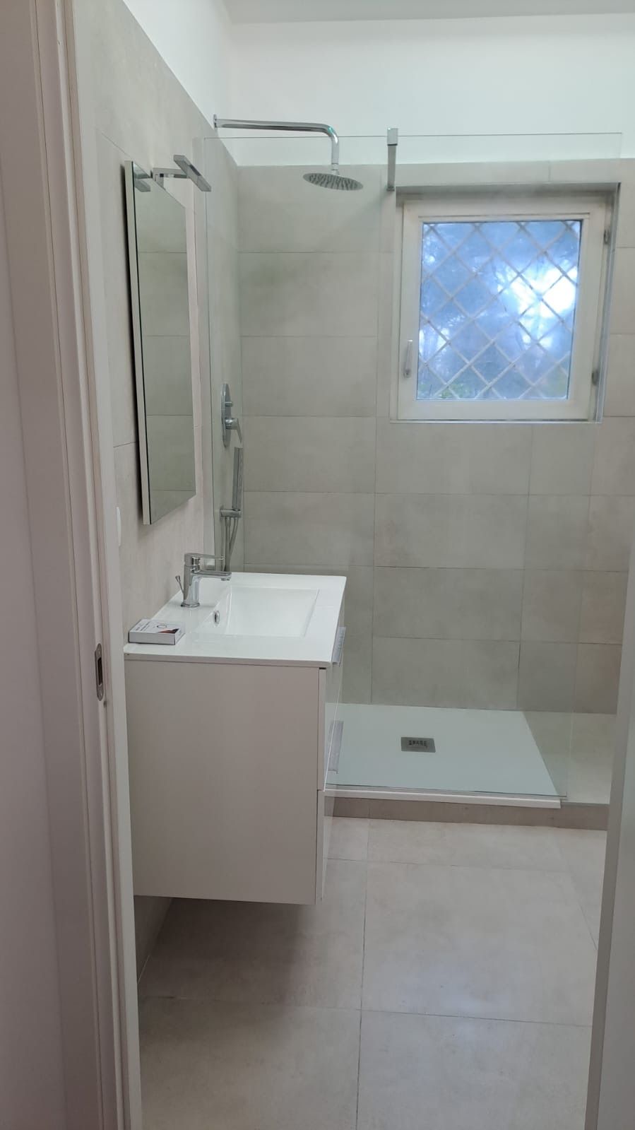 Un bagno con lavandino, specchio e cabina doccia.