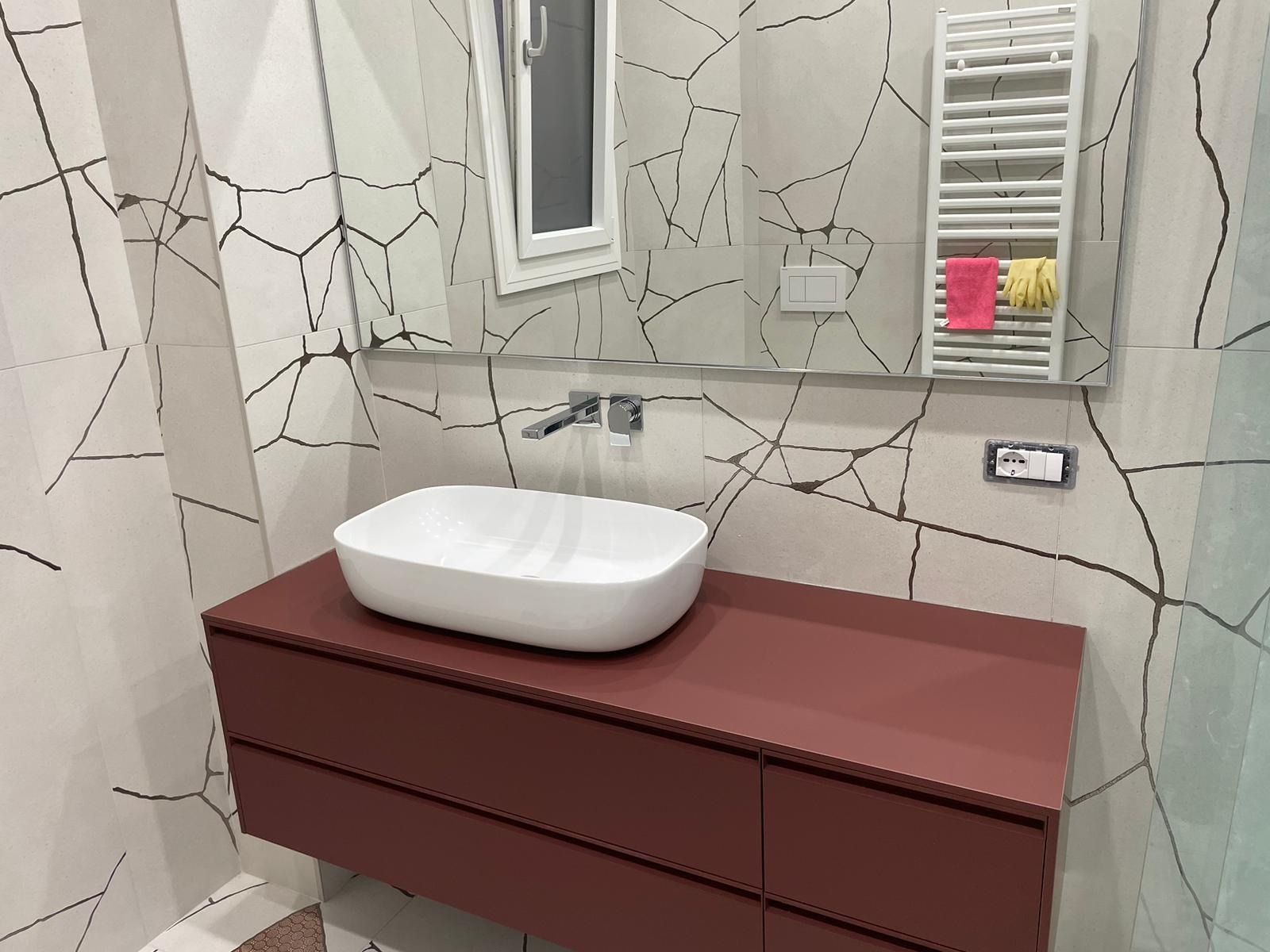 Un bagno con lavandino, specchio e portasciugamani