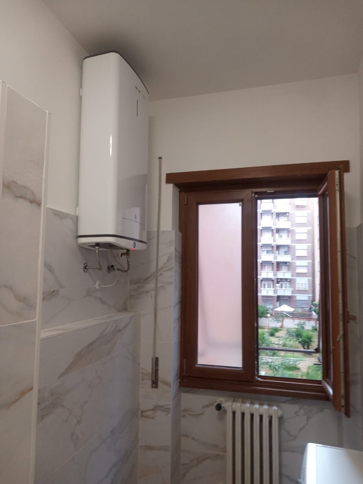 Un bagno con una finestra e un termosifone bianco