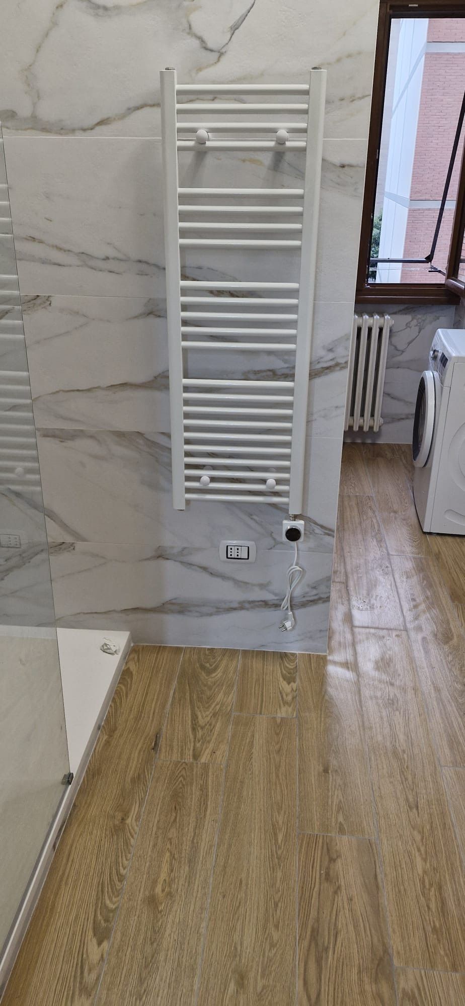 Un bagno con portasciugamani a parete e pavimento in legno.