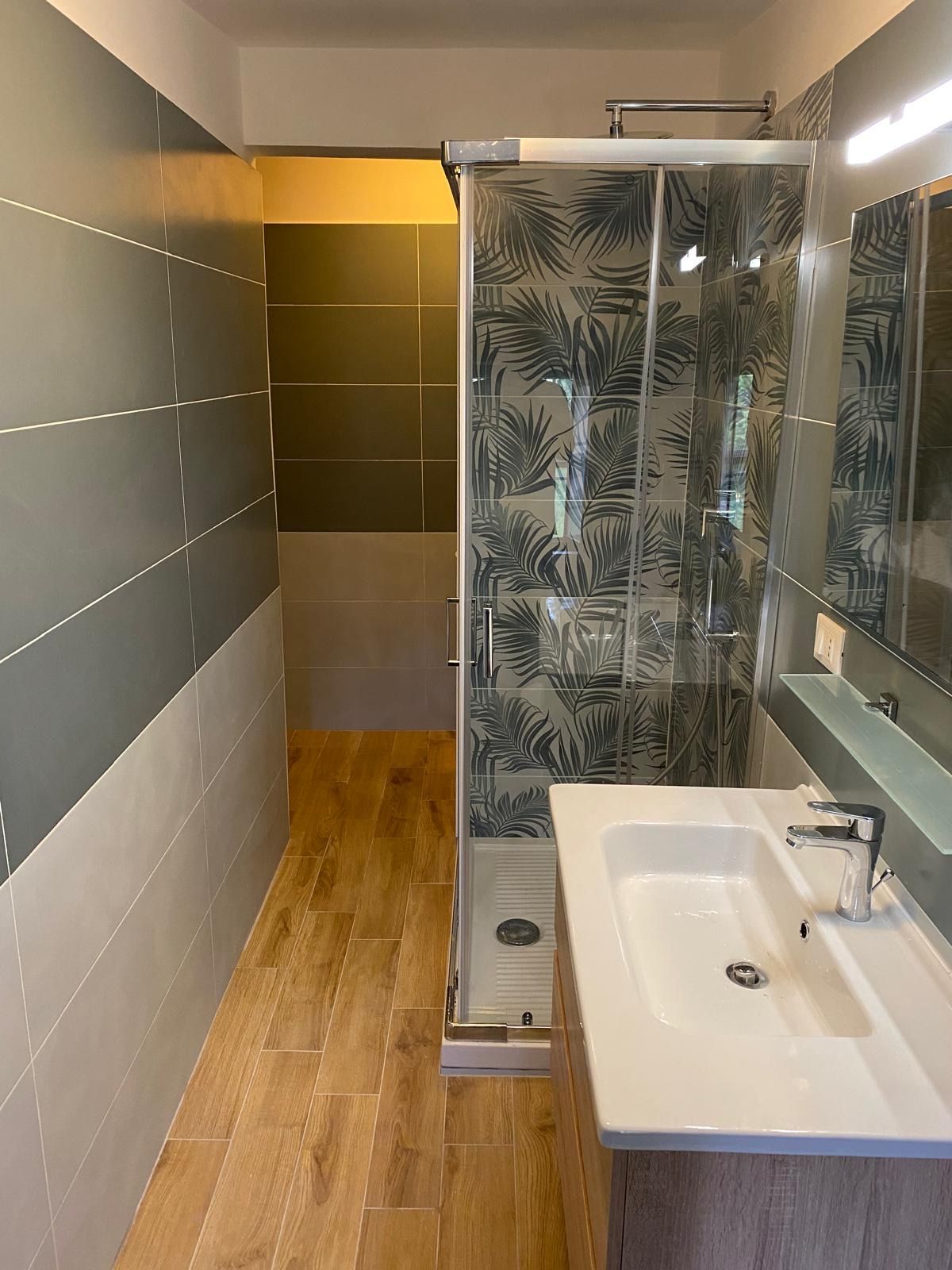 Un bagno con lavandino, doccia e specchio.