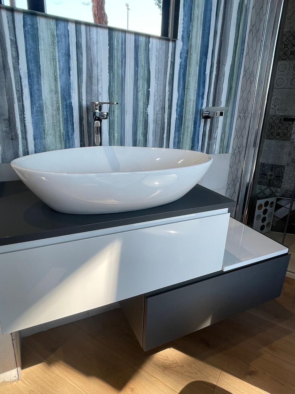 Un lavandino bianco è appoggiato su un ripiano bianco in un bagno.