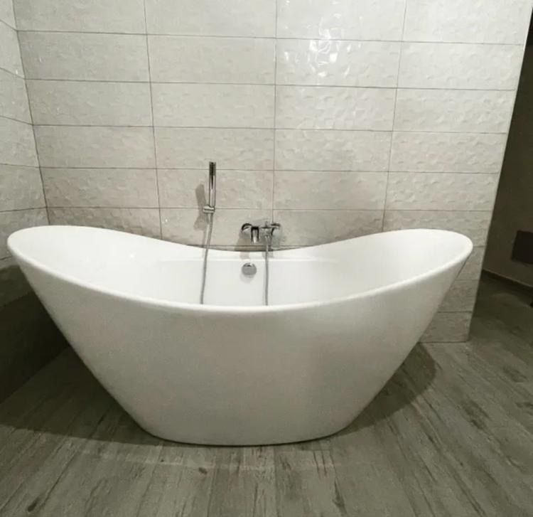 Una vasca da bagno bianca è appoggiata su un pavimento di legno in un bagno.