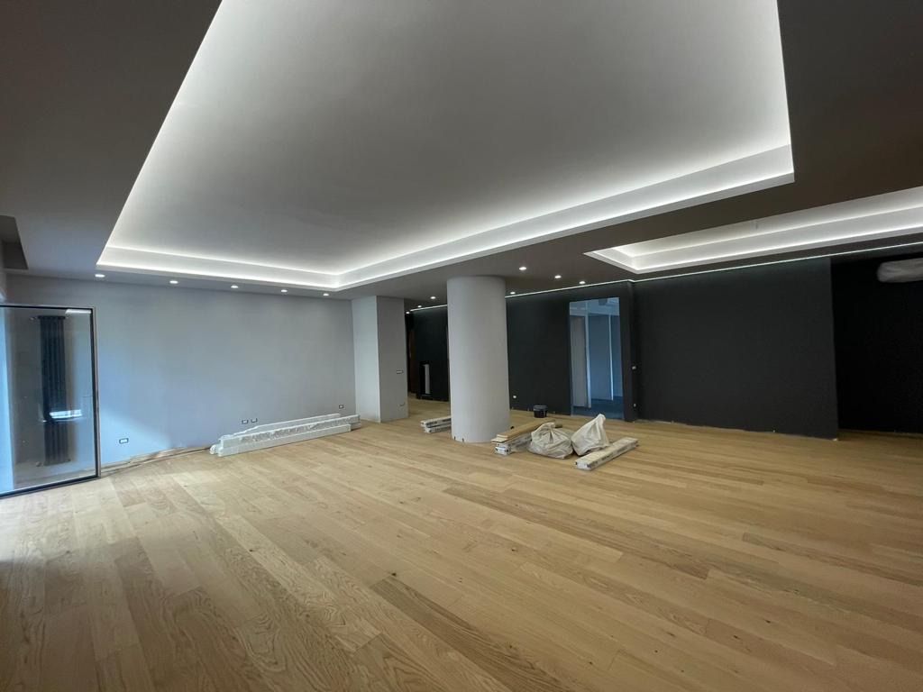 Una grande stanza vuota con pavimenti in legno e un soffitto bianco.