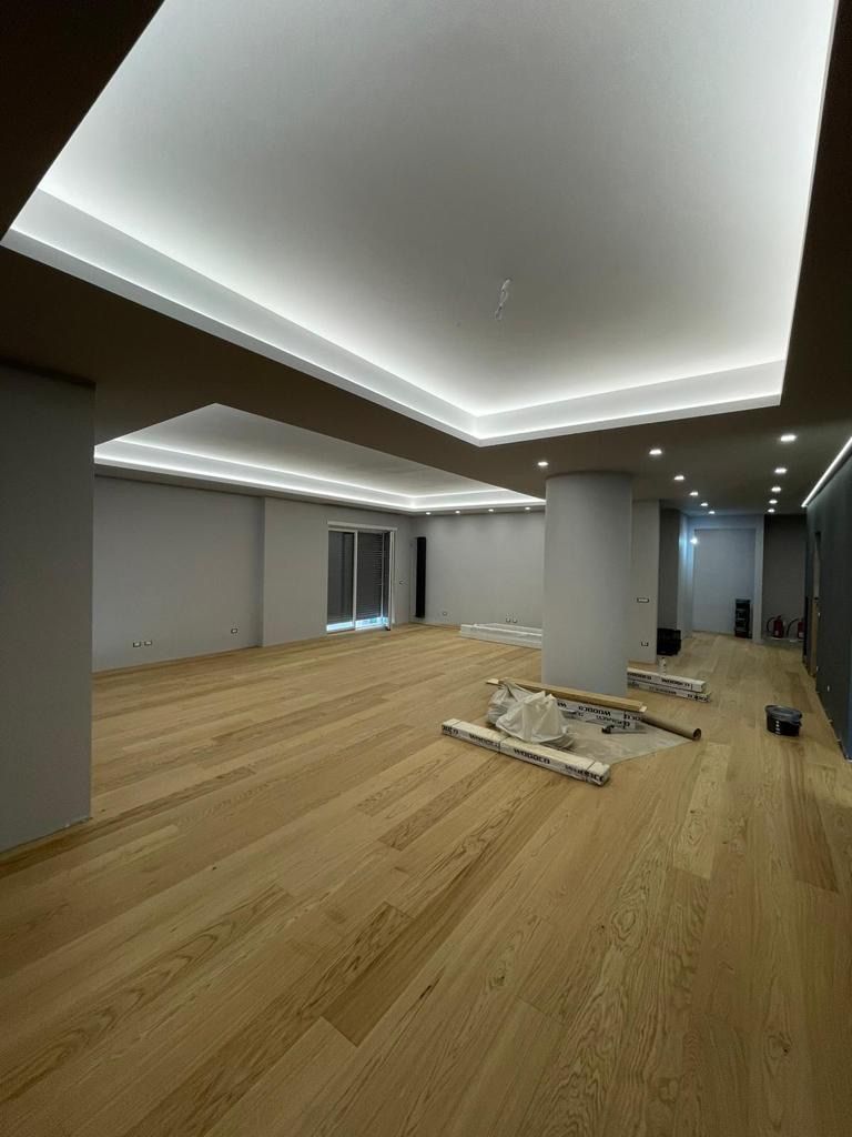 Una grande stanza vuota con pavimenti in legno e un soffitto bianco.