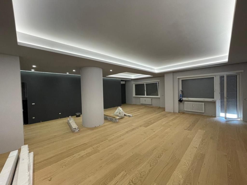 Una grande stanza vuota con pavimenti in legno e un soffitto bianco.