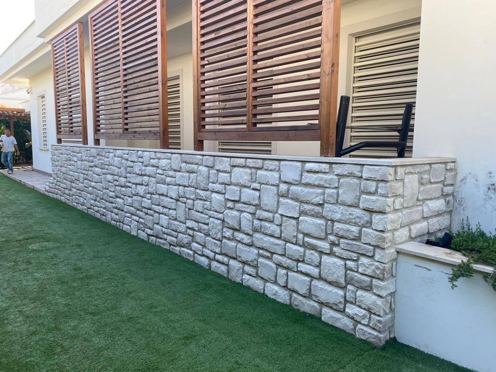 Un muro di pietra con persiane di legno alle finestre di una casa.