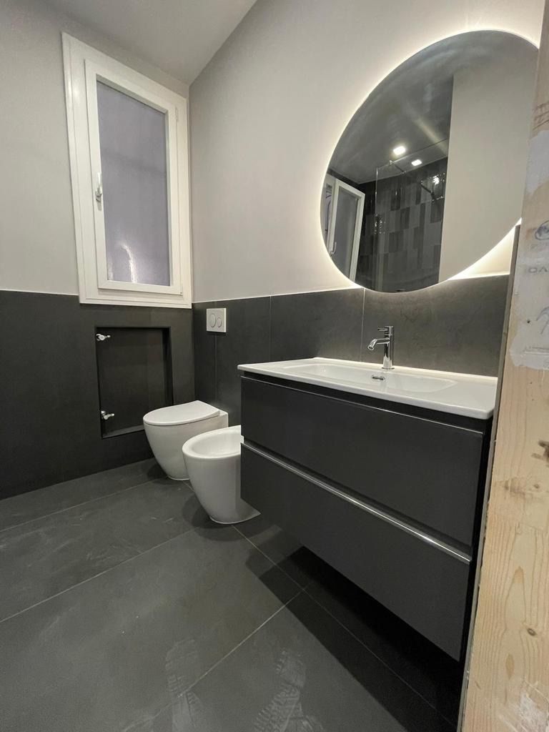 Un bagno con due wc, un lavandino e uno specchio.