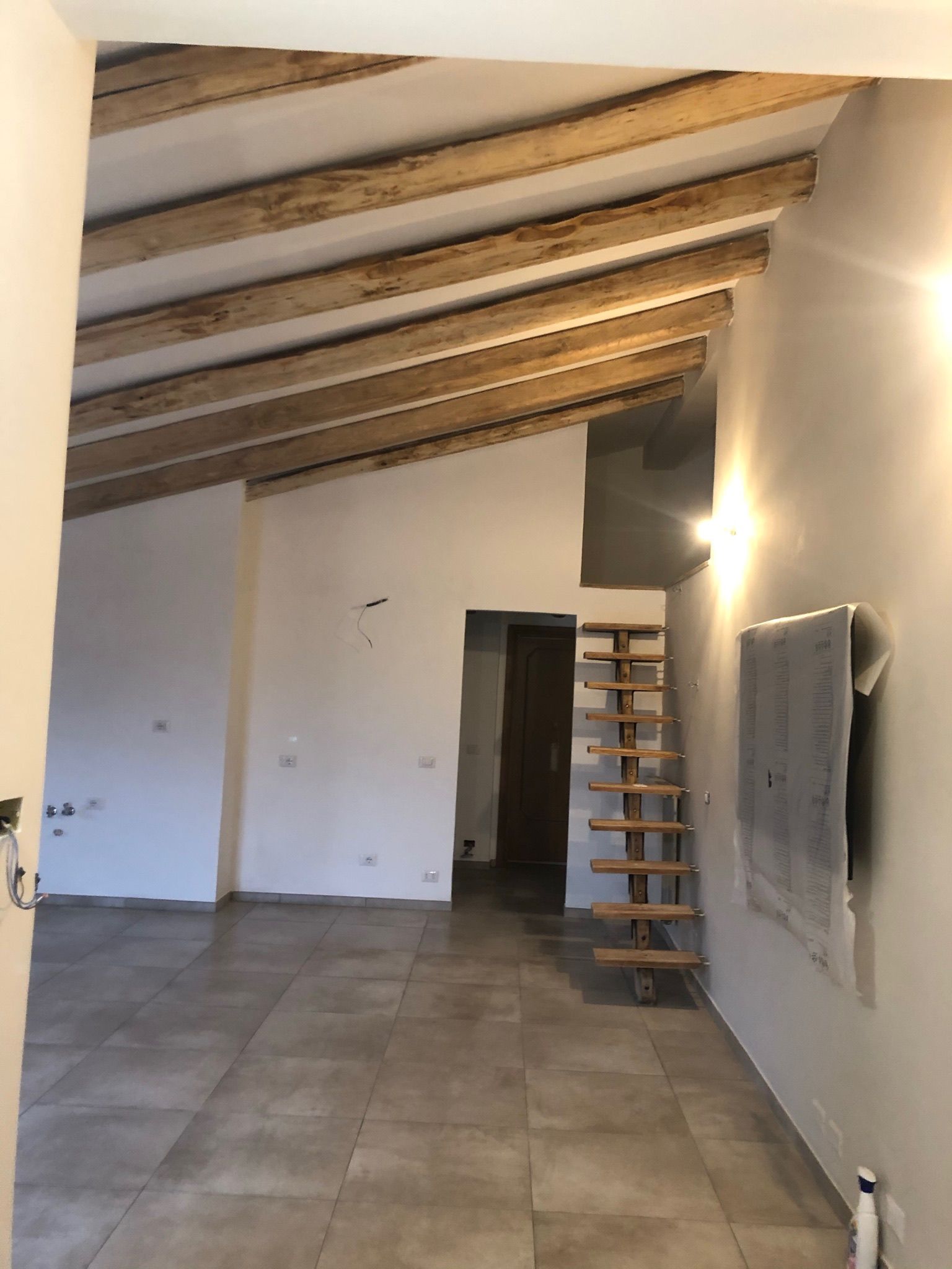 Una stanza vuota con travi di legno e una scala