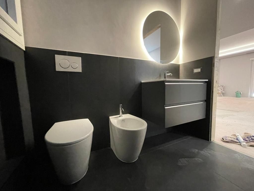Un bagno con wc, bidet, lavandino e specchio.