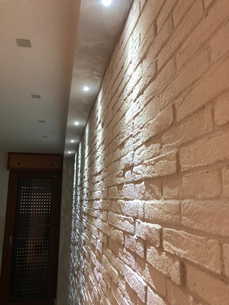 Un corridoio con un muro di mattoni bianchi e luci sul soffitto.
