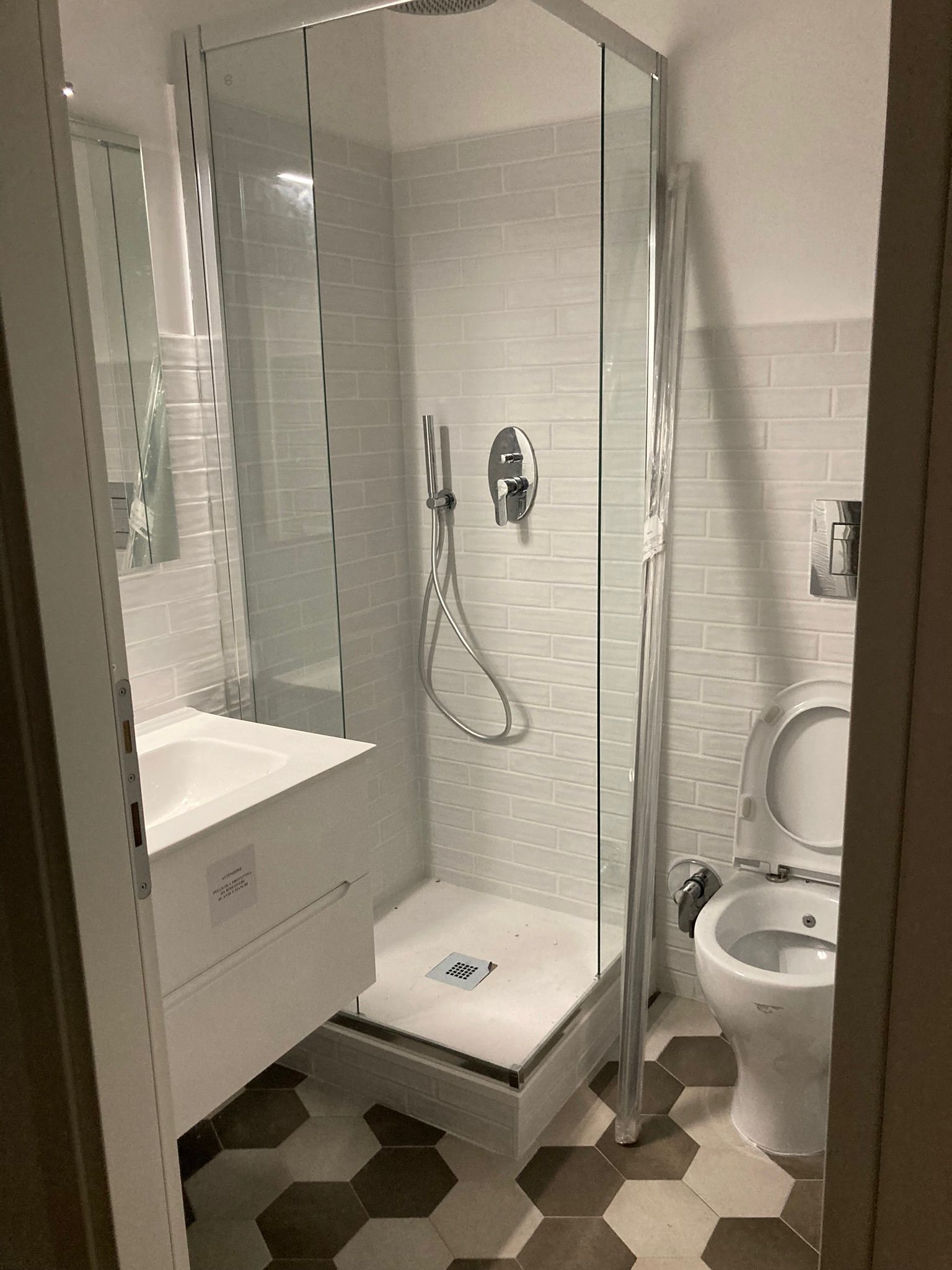 Un bagno con wc, lavandino, doccia e specchio.